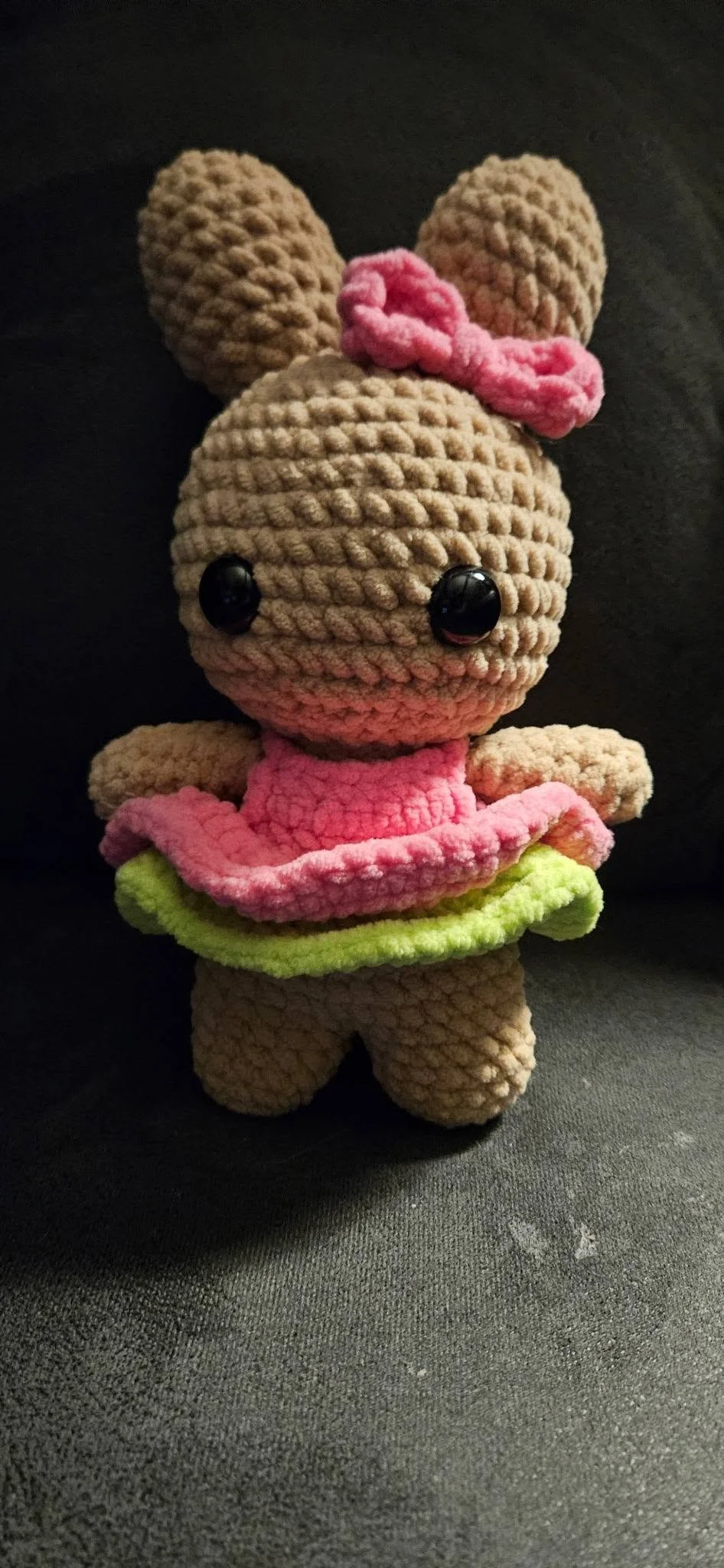 Handmade crochet bunny stuffed animal with a pink and green layered dress and a pink bow.