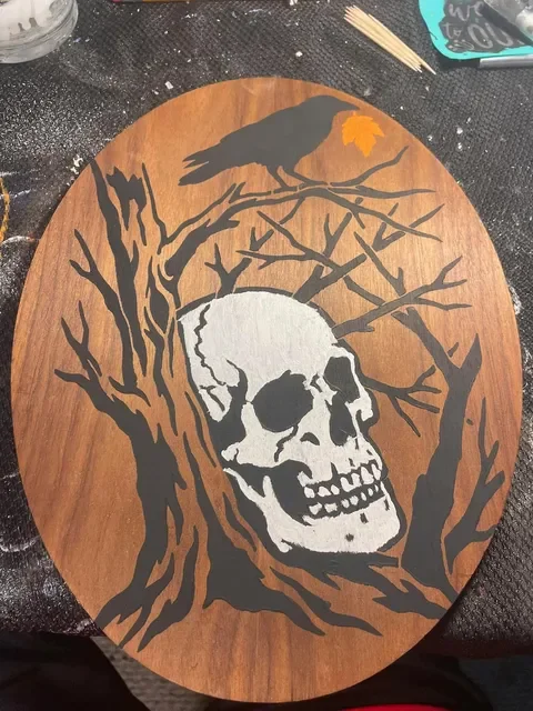 Painted wood plaque featuring crow, branches, and skull created by This and That Crafts.