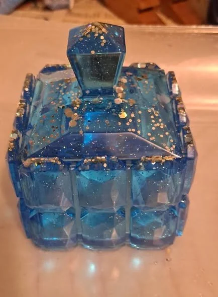 Faceted blue resin trinket box with gold glitter and matching lid handle.