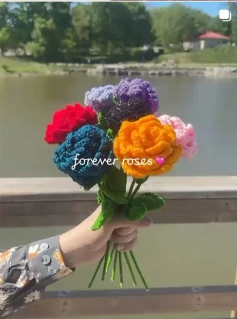 Handmade crochet rose bouquet in multicolor shades with green stems, crafted by Meraki The Soul Creativity and photographed outdoors near a lake in Waterloo, Iowa.