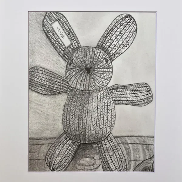 A detailed pencil drawing of a knitted stuffed bunny with textured stitching, long ears, round eyes, and a small tag reading “17 April.”
