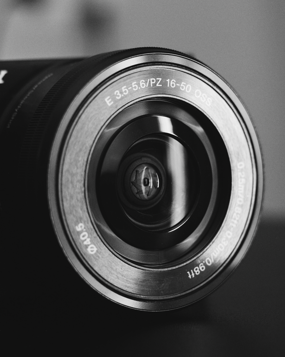 Close-up of a camera lens with specifications inscribed on it, in black and white.