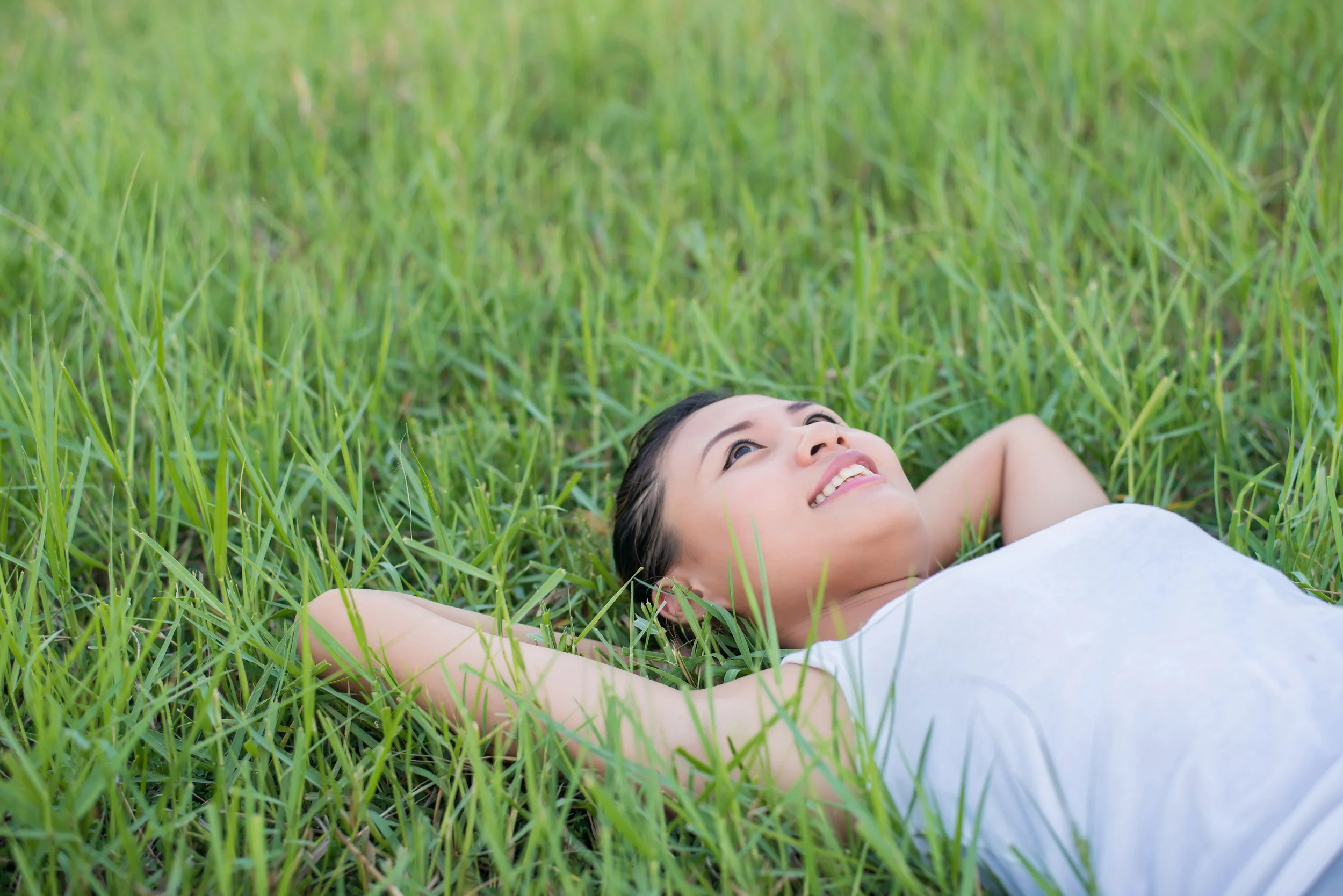vecteezy_beautiful-young-woman-lying-down-in-green-grass-meadows_5206696.jpg