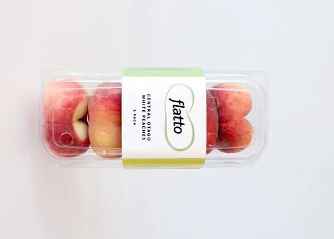 Clear plastic container of peach and red grape fruit snacks with Flatto label on top.