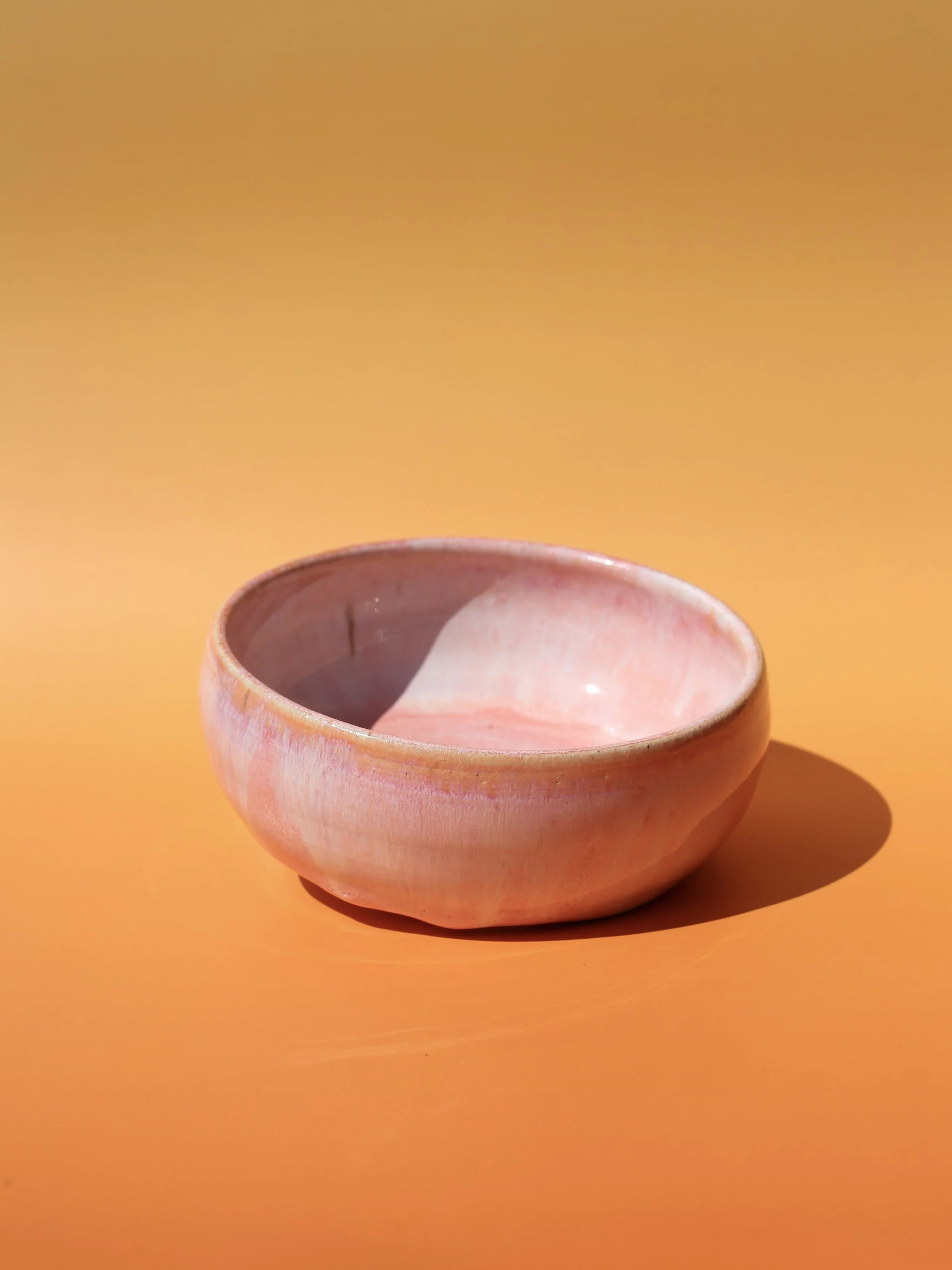 Pink ceramic bowl on an orange background.