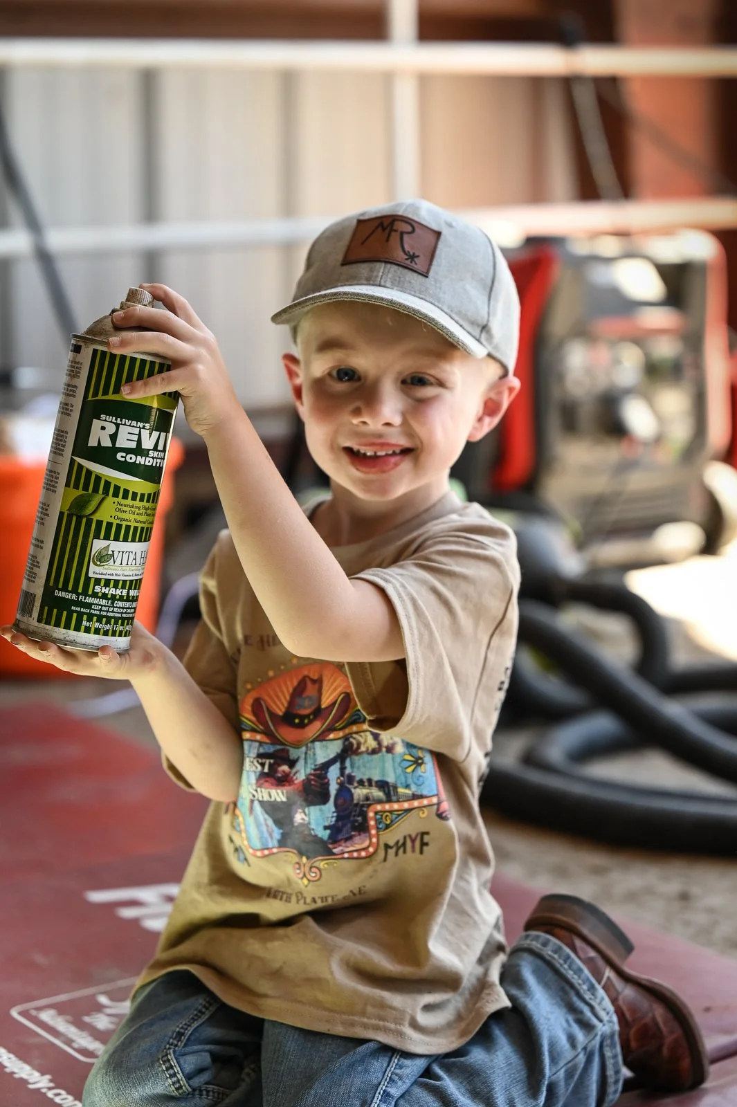 A Pre-Junior exhibitor competing in the Fitting Contest at the Miniature Hereford Junior Nationals, smiling and holding a can of Sullivan's REV skin conditioner.