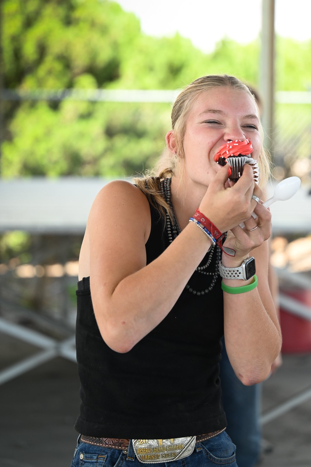 A senior exhibitor at the Miniature Hereford Junior Nationals participates in fun at games at the event.  She is competing in a relay race and shoving a red iced cupcake in her mouth as fast as she can