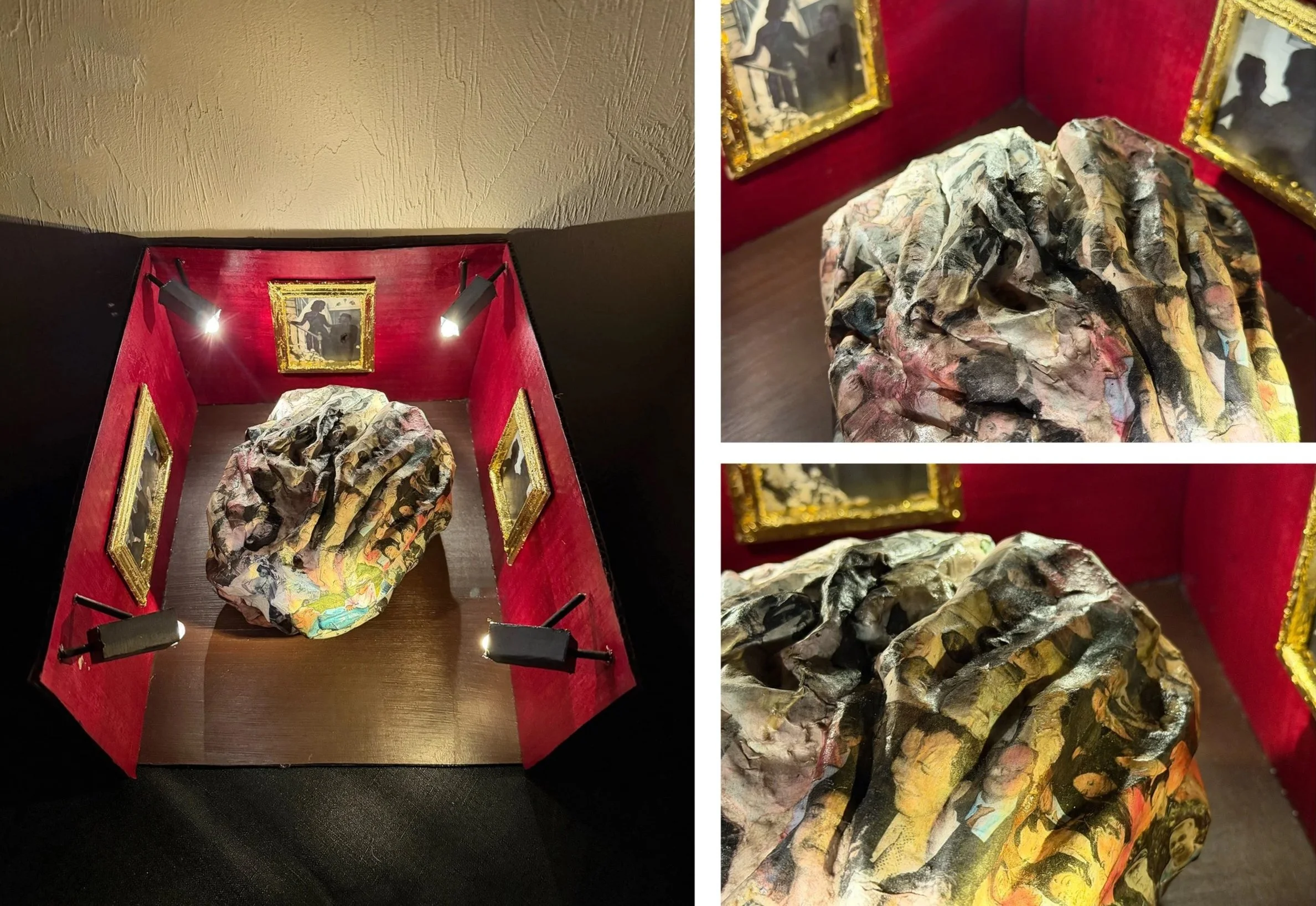 A red display case with black spotlights, housing a colorful, textured sculpture and framed artwork on the walls.