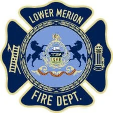 Badge of the Lower Merion Fire Department featuring a Maltese cross with firefighting symbols and text.