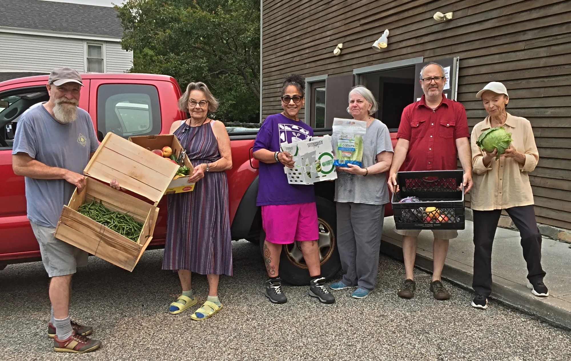 six volunteers holding up boxes of vegetables