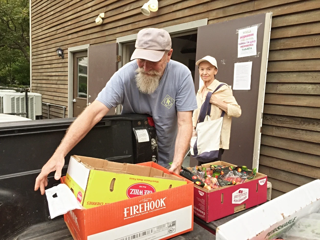 A food distribution with fresh produce and WMLA volunteers preparing to sort it.
