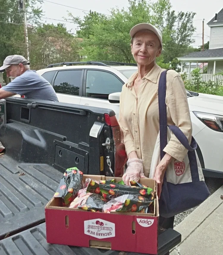 woman standing holding box of food