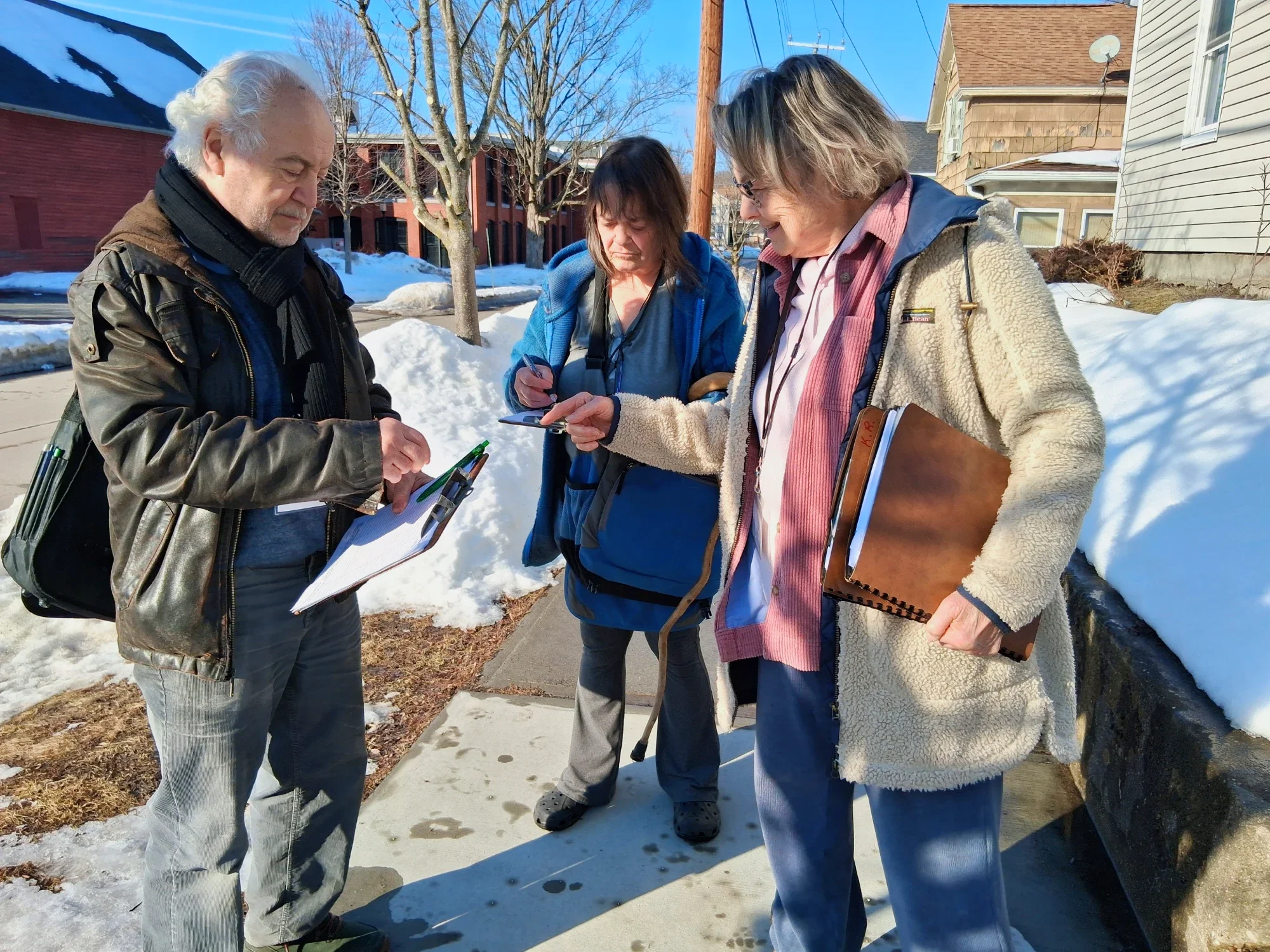 A woman outside signing up as a member next to two volunteers