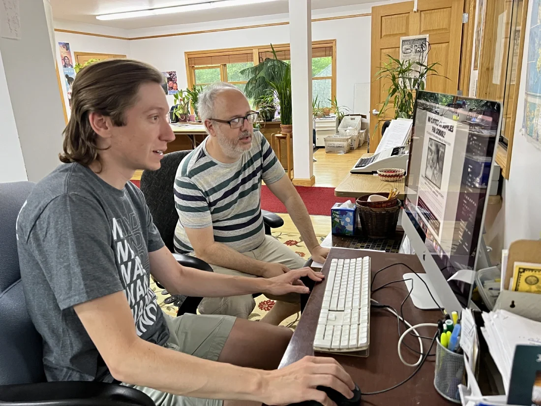 Two people working at a desktop computer.