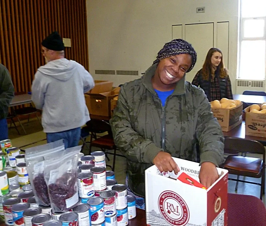 A woman smiling as she fills a box with food items