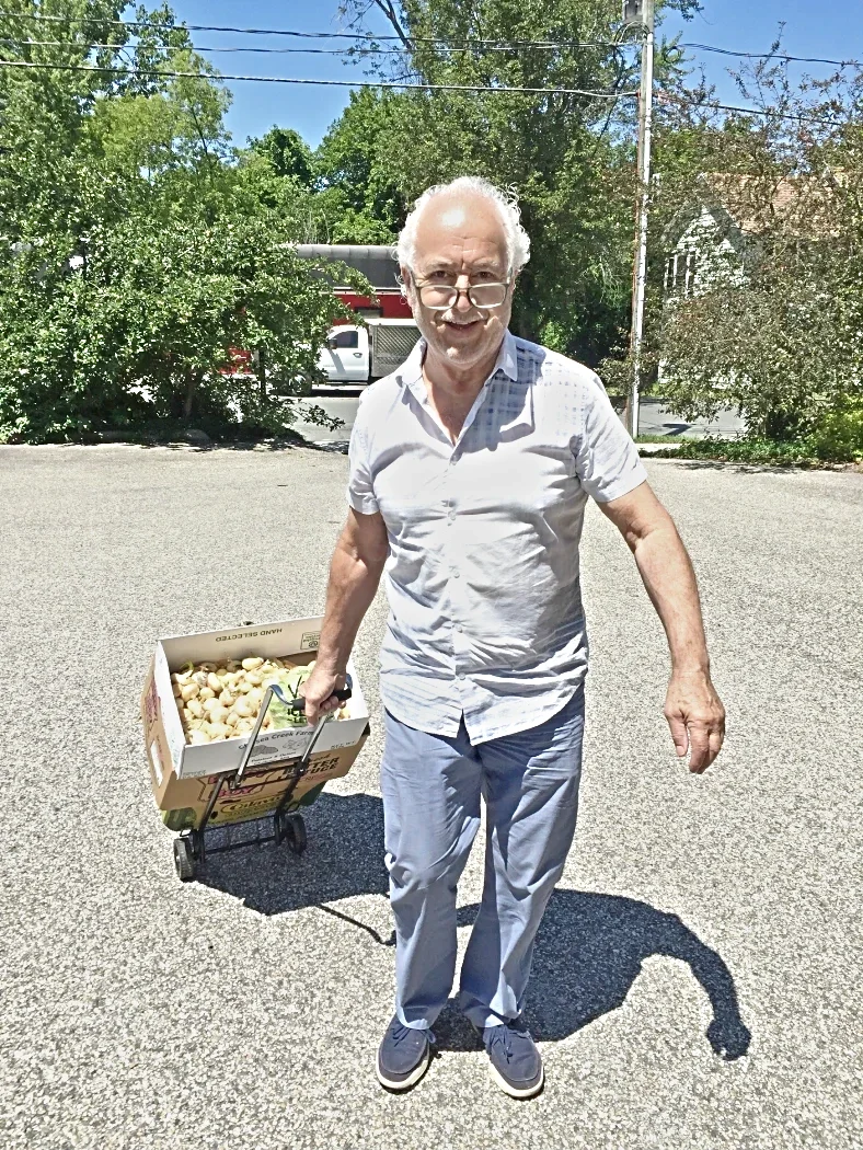 Man pulling dolly with box of vegetables