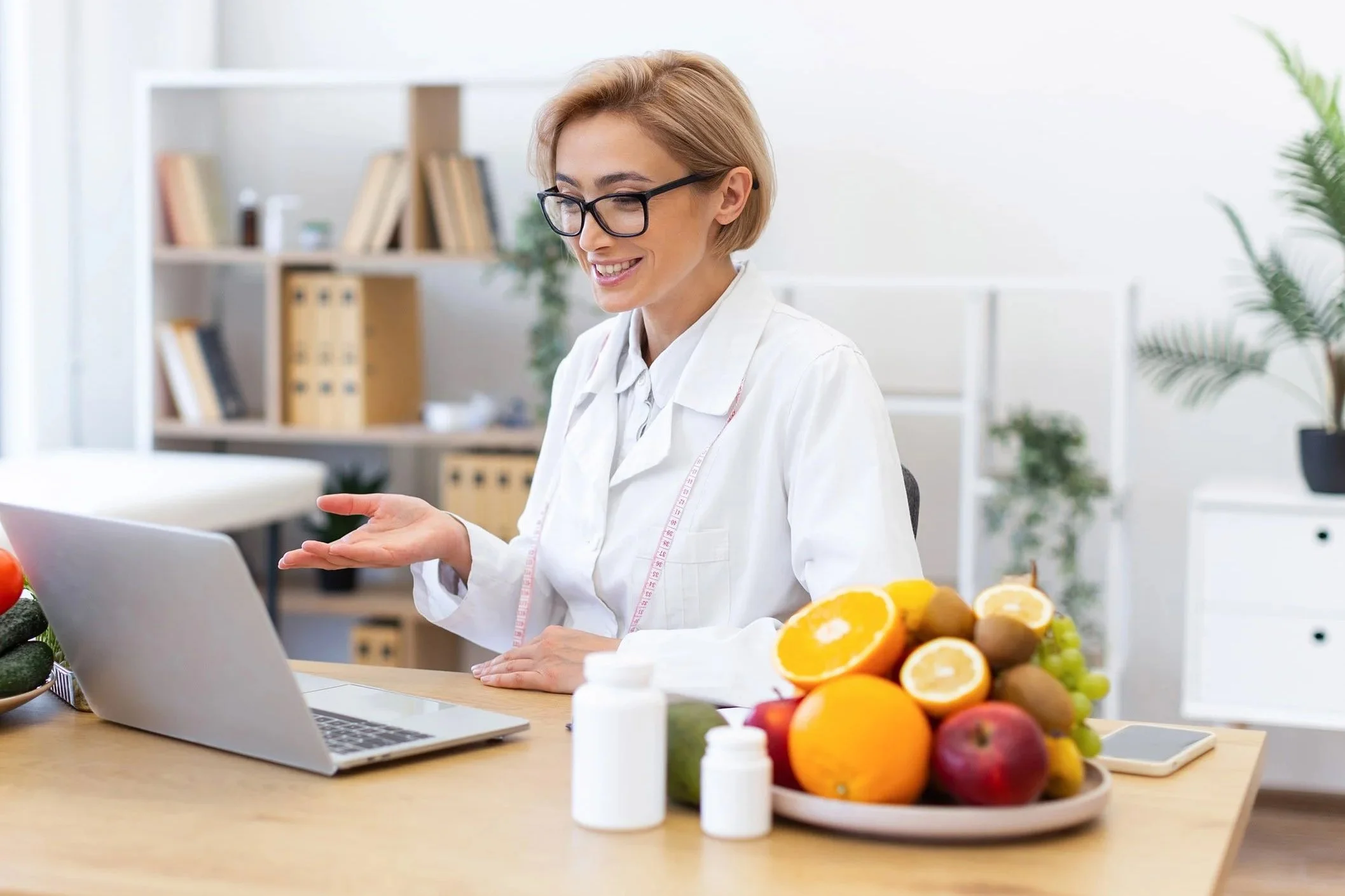 A smiling female Registered Dietitian conducts a telehealth appointment using a laptop and a secure video conference connection.