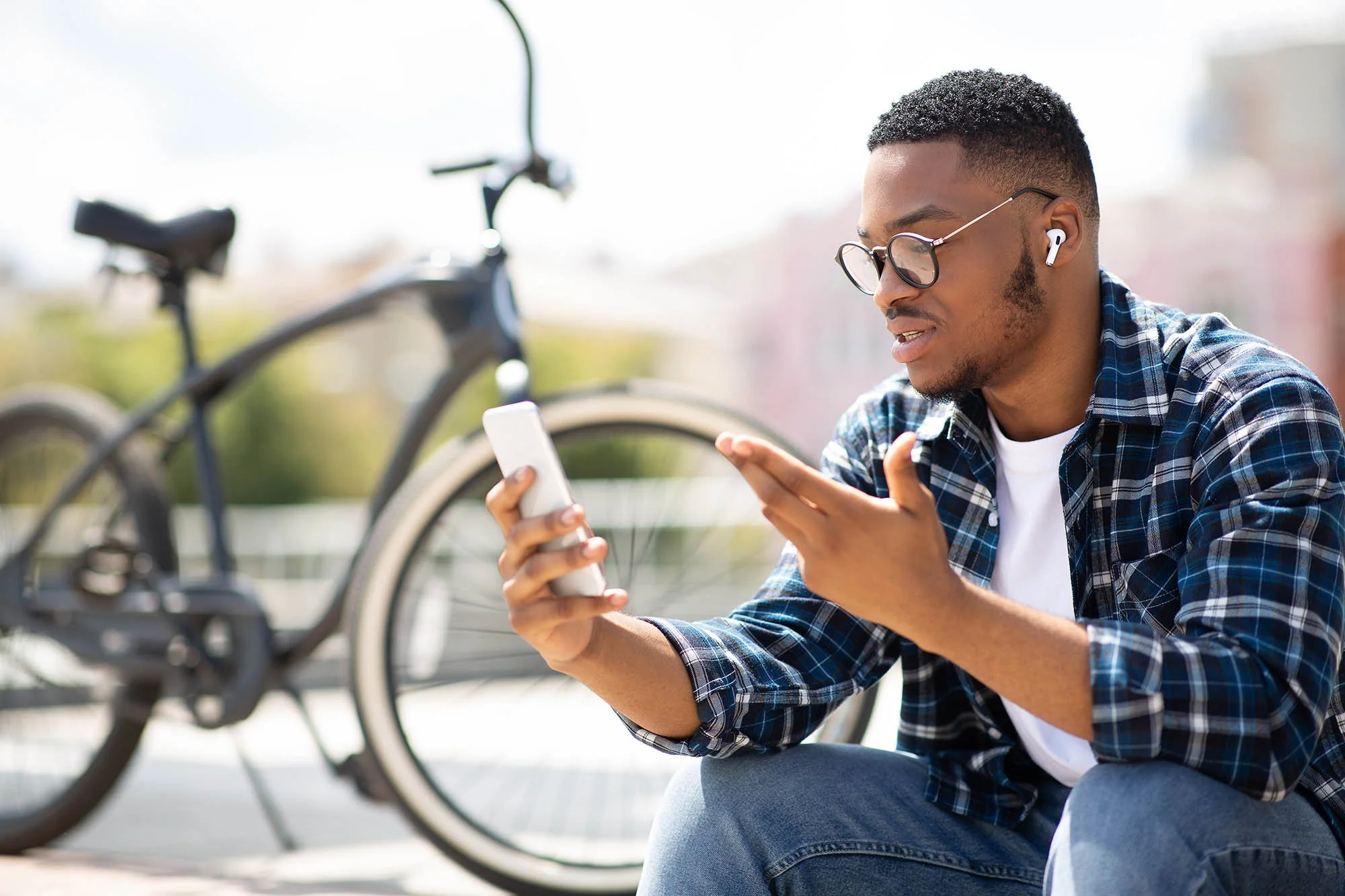 A young man pauses in the middle of a bike ride to receive a telehealth appointment from The Dietitian's Office using his smart phone.