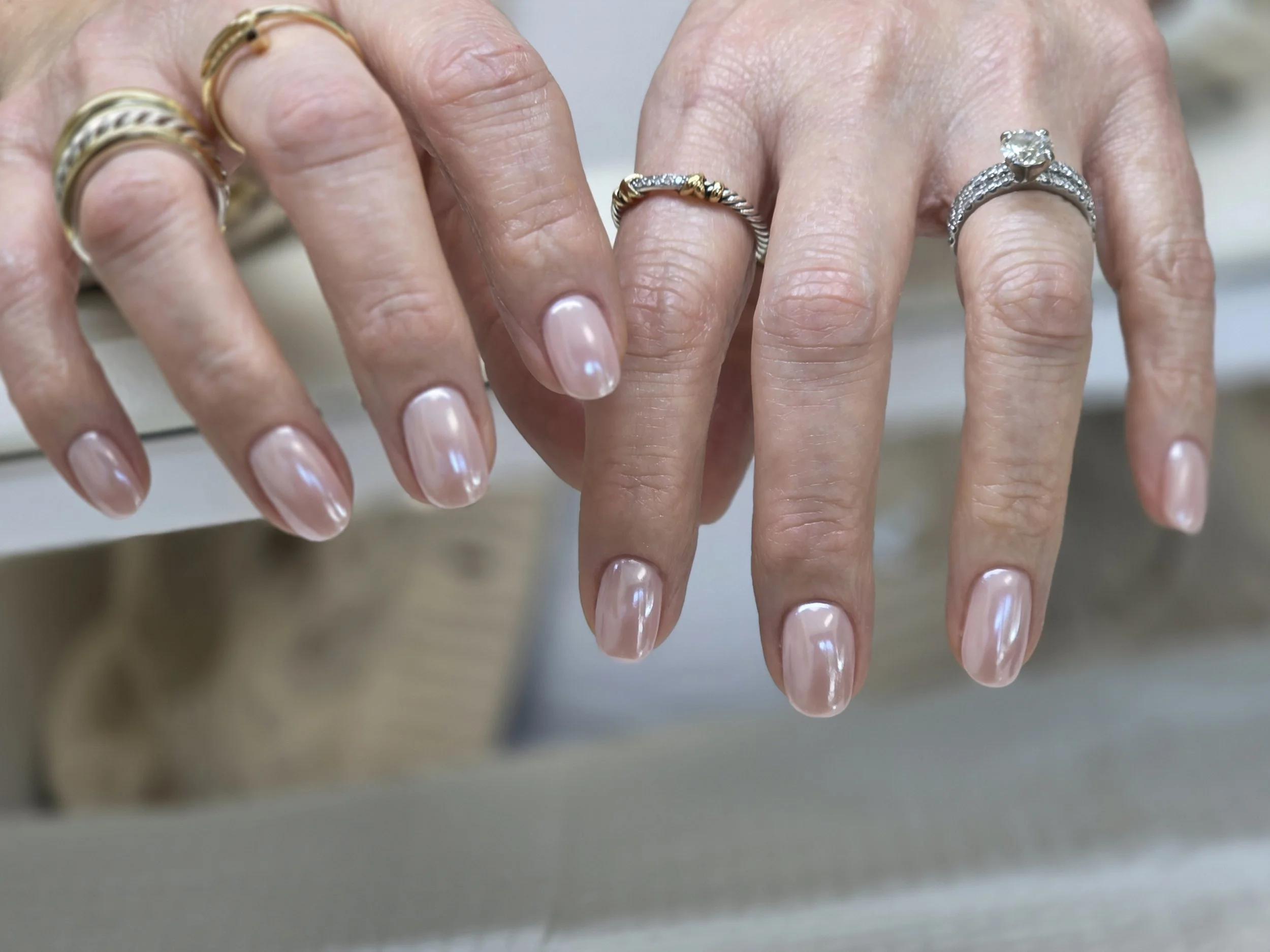 Close-up of hands displaying multiple rings, including a large engagement ring with a central diamond and silver and gold bands.