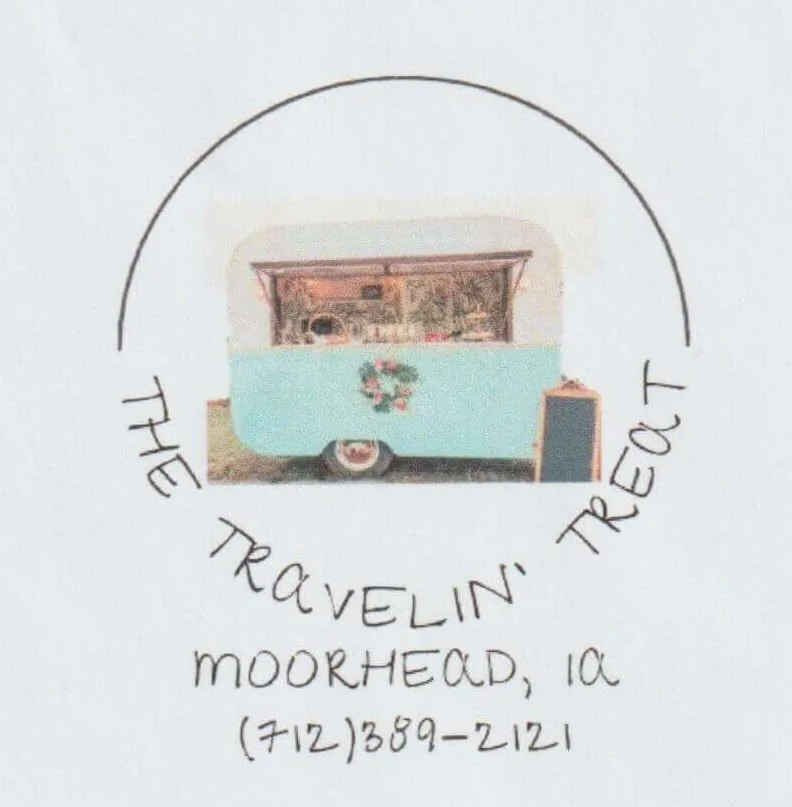 A logo for The Traveling TrEAt, a food truck in Moorhead, Iowa, featuring an illustration of a light blue vintage trailer with a wreath decoration, circled by handwritten text.