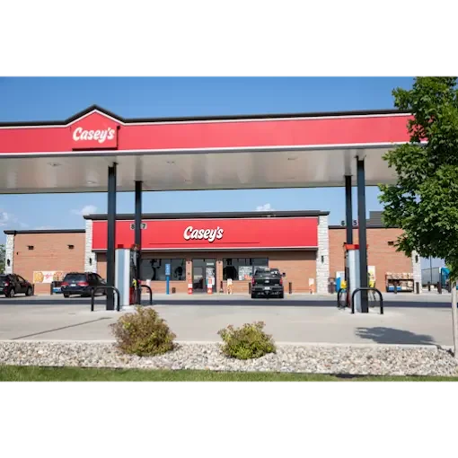Casey's gas station with convenience store and fueling pumps, cars parked, and a tree in the foreground.