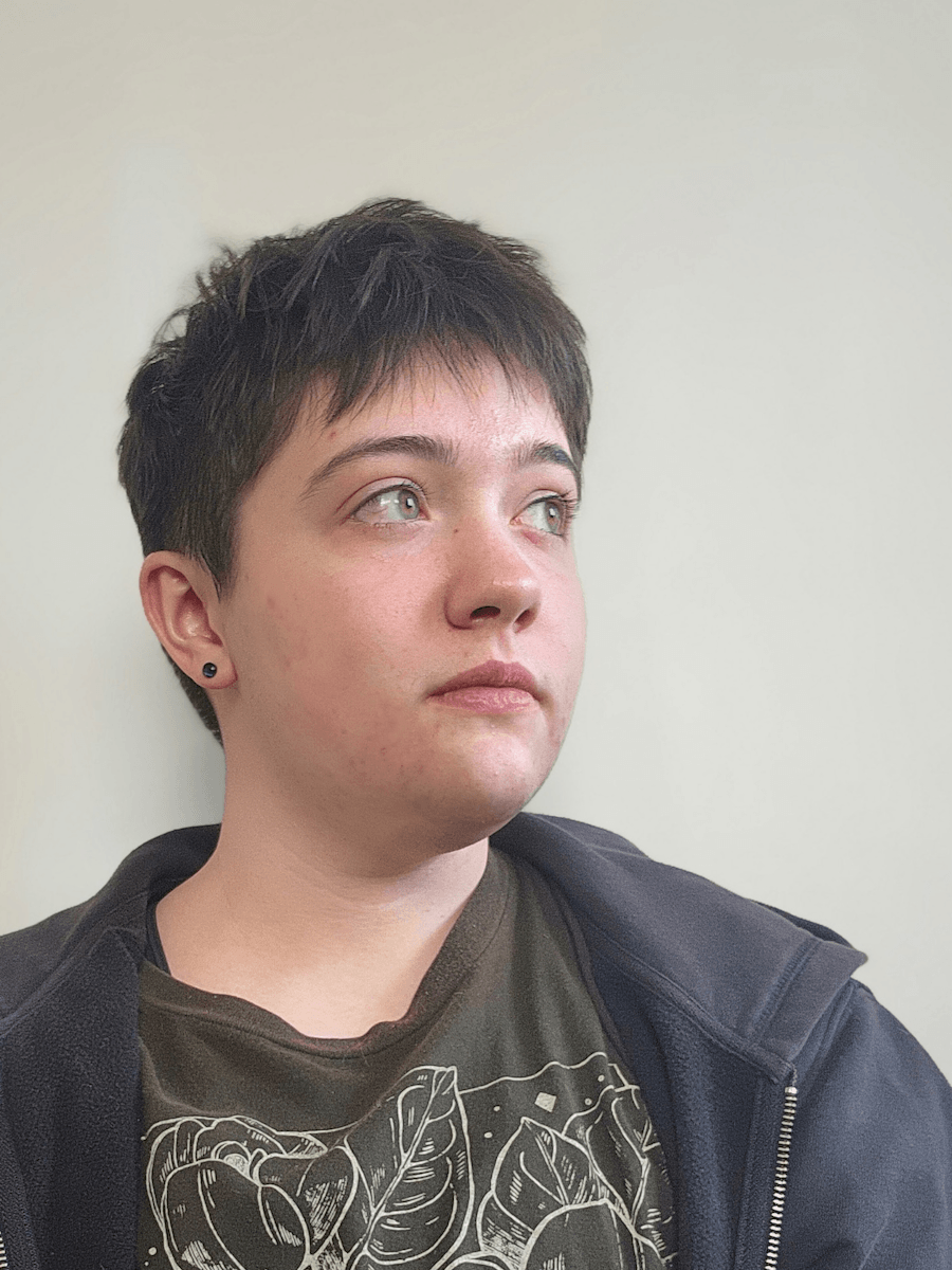 photo of artist Jordan Carinae from shoulders up looking up and to the left wearing a dark grey hoodie and graphic tshirt