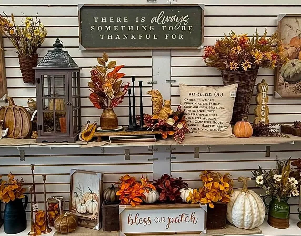 Fall-themed decorative display with pumpkins, flowers, and a sign that reads 'there is always something to be thankful for.'
