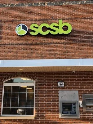 SCSB bank sign on brick wall with ATM and window below