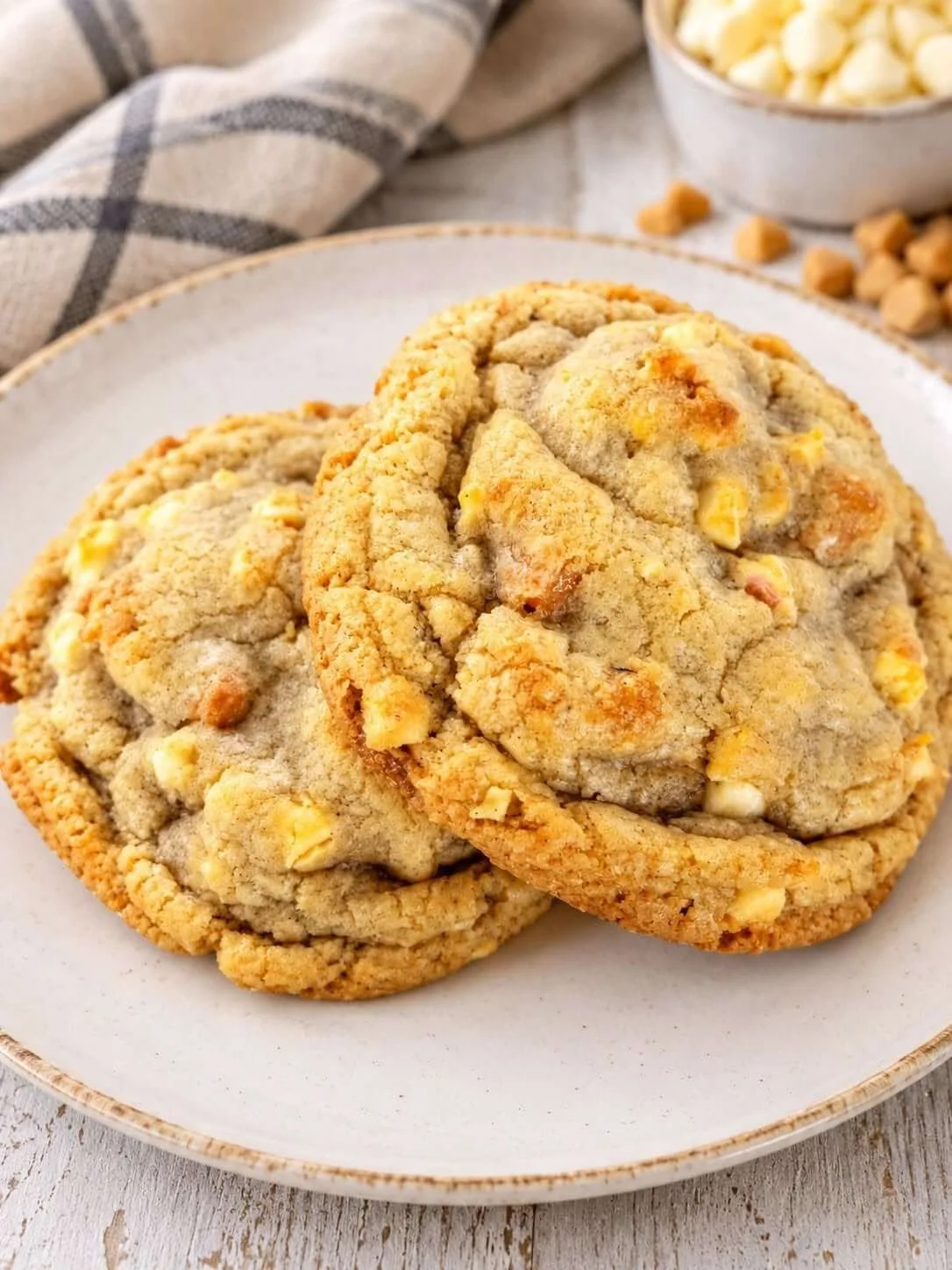 Two large cookies with white chocolate chips on a white plate.