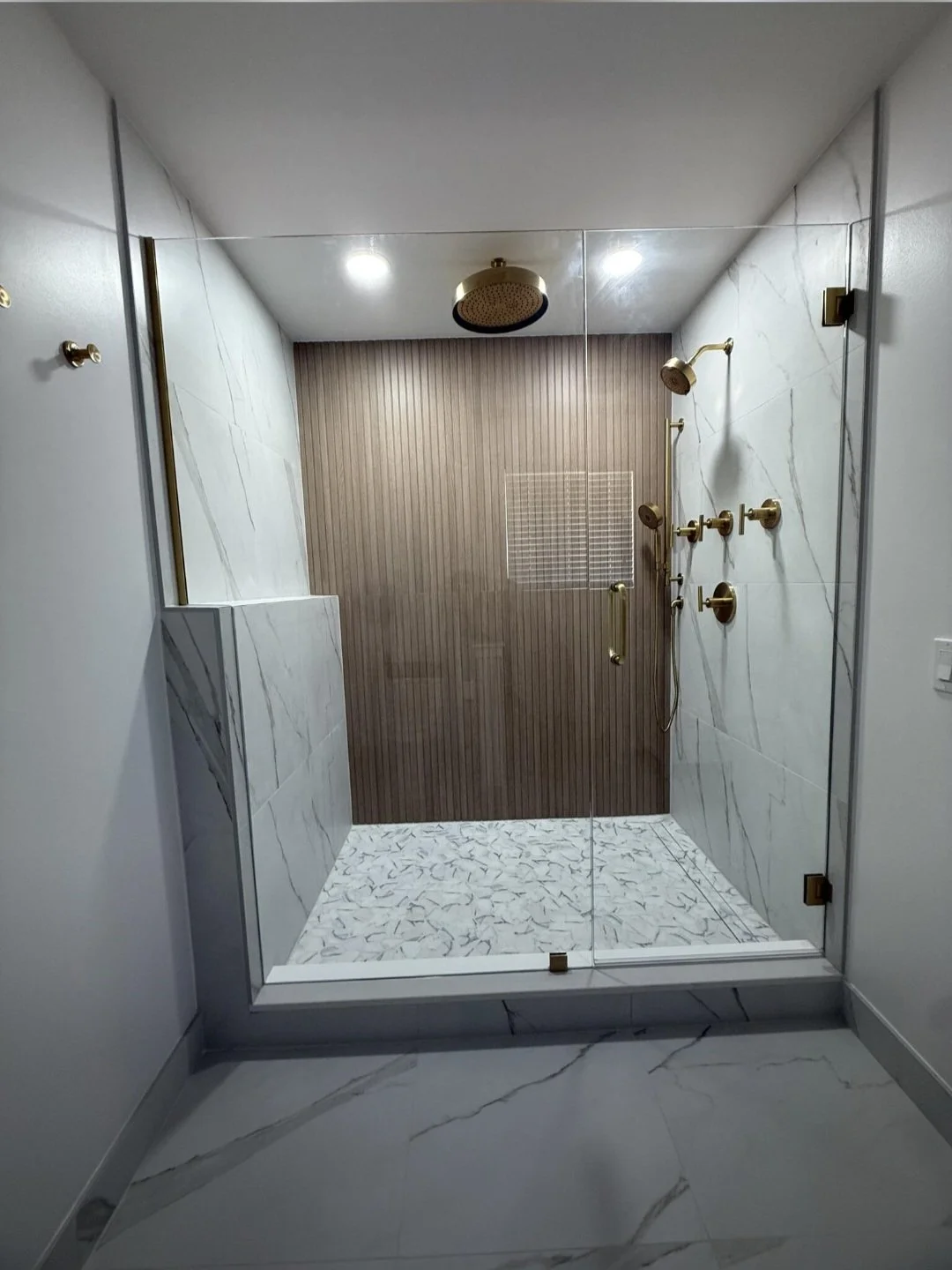 A spacious walk-in shower featuring large-format tile, recessed lighting, and a sleek modern design that creates a luxurious spa-like experience.