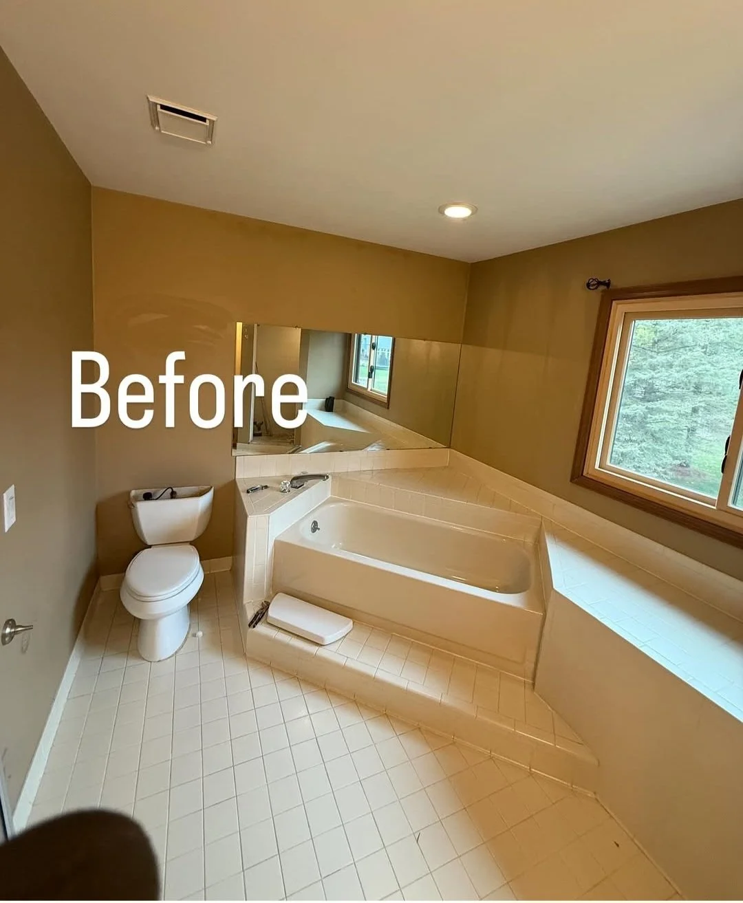 Bathroom with a toilet, bathtub, large window, and mirror on the wall.