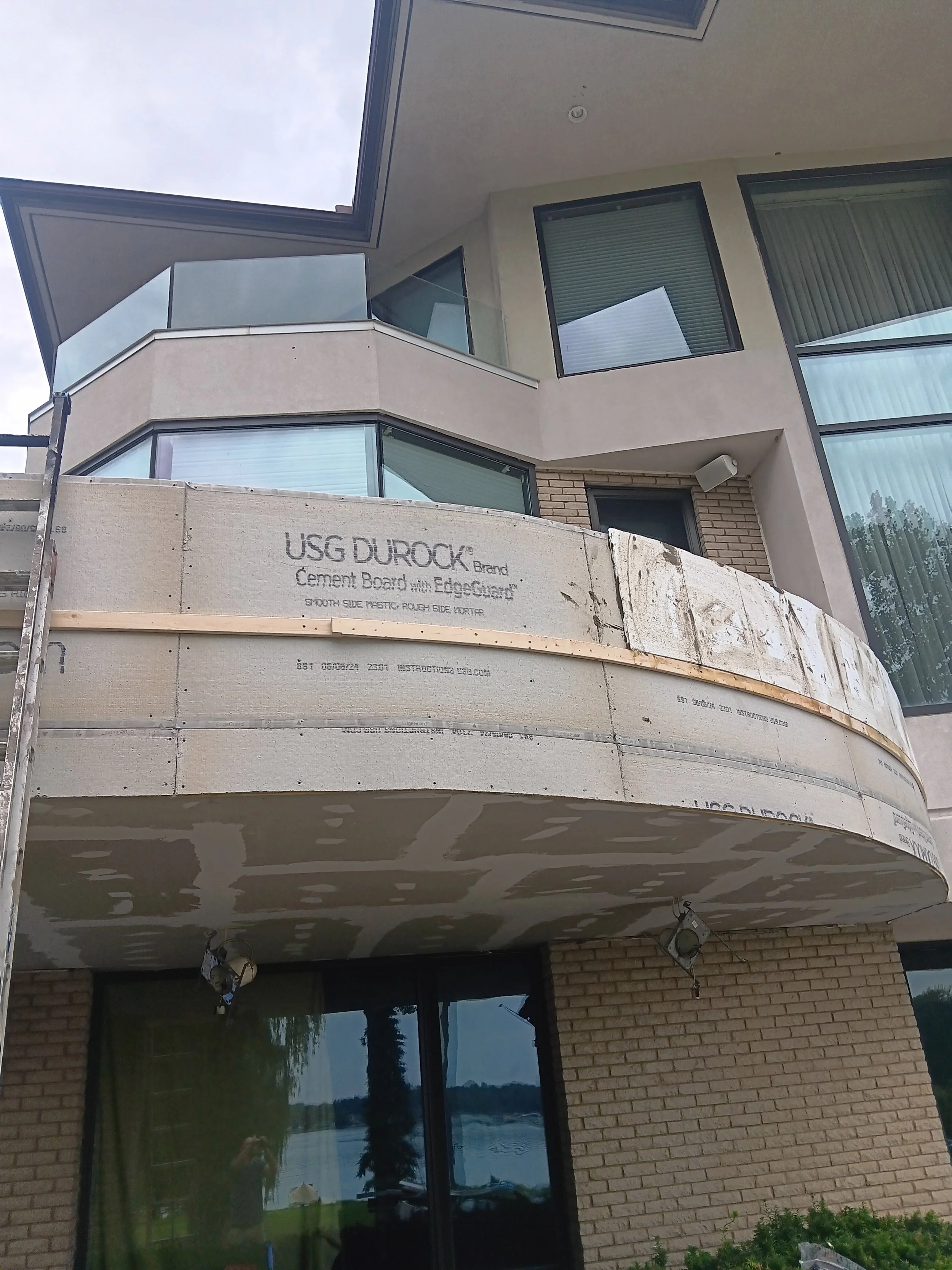 Restored curved balcony with a smooth finished exterior, updated railings, and a clean modern appearance.