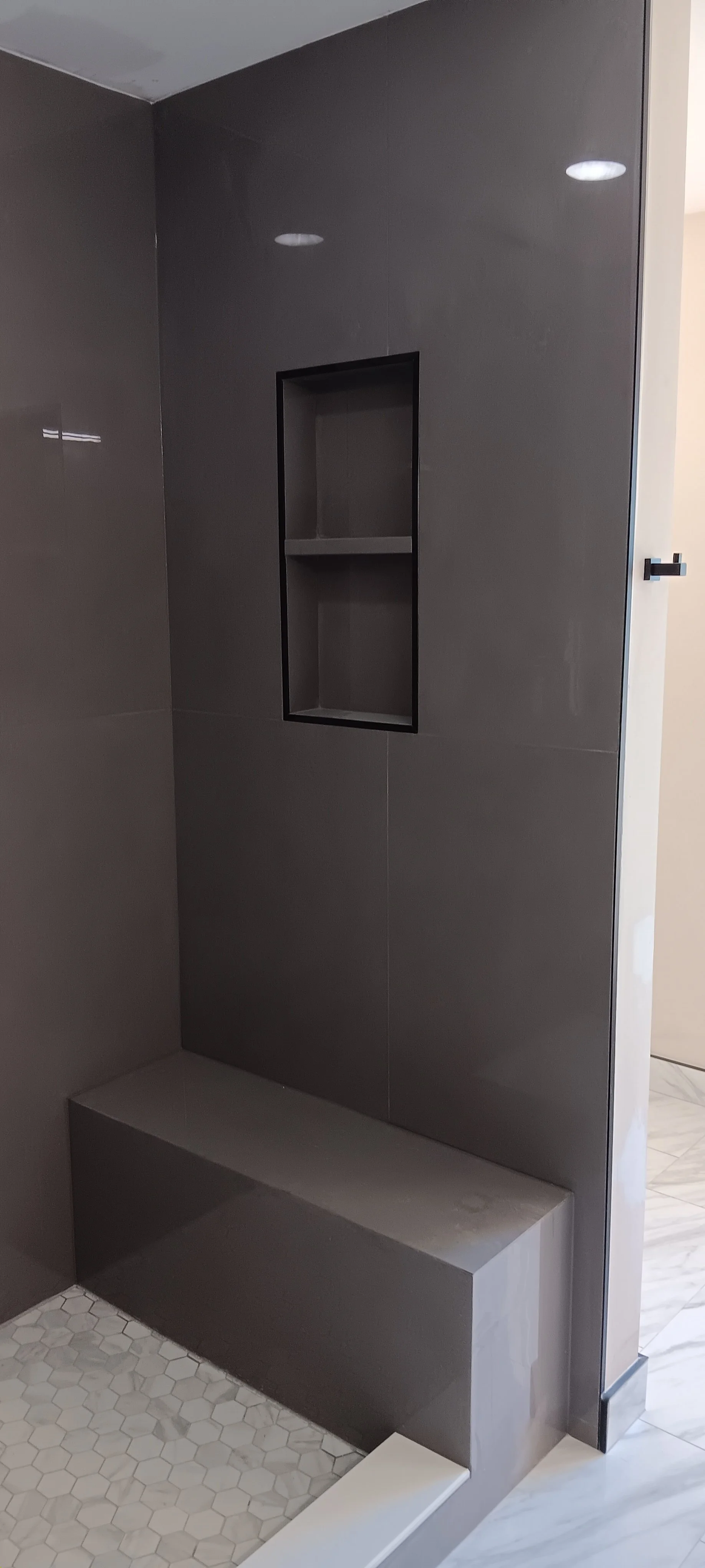 Custom walk-in shower with built-in niche, bench, modern tile, and recessed lighting.