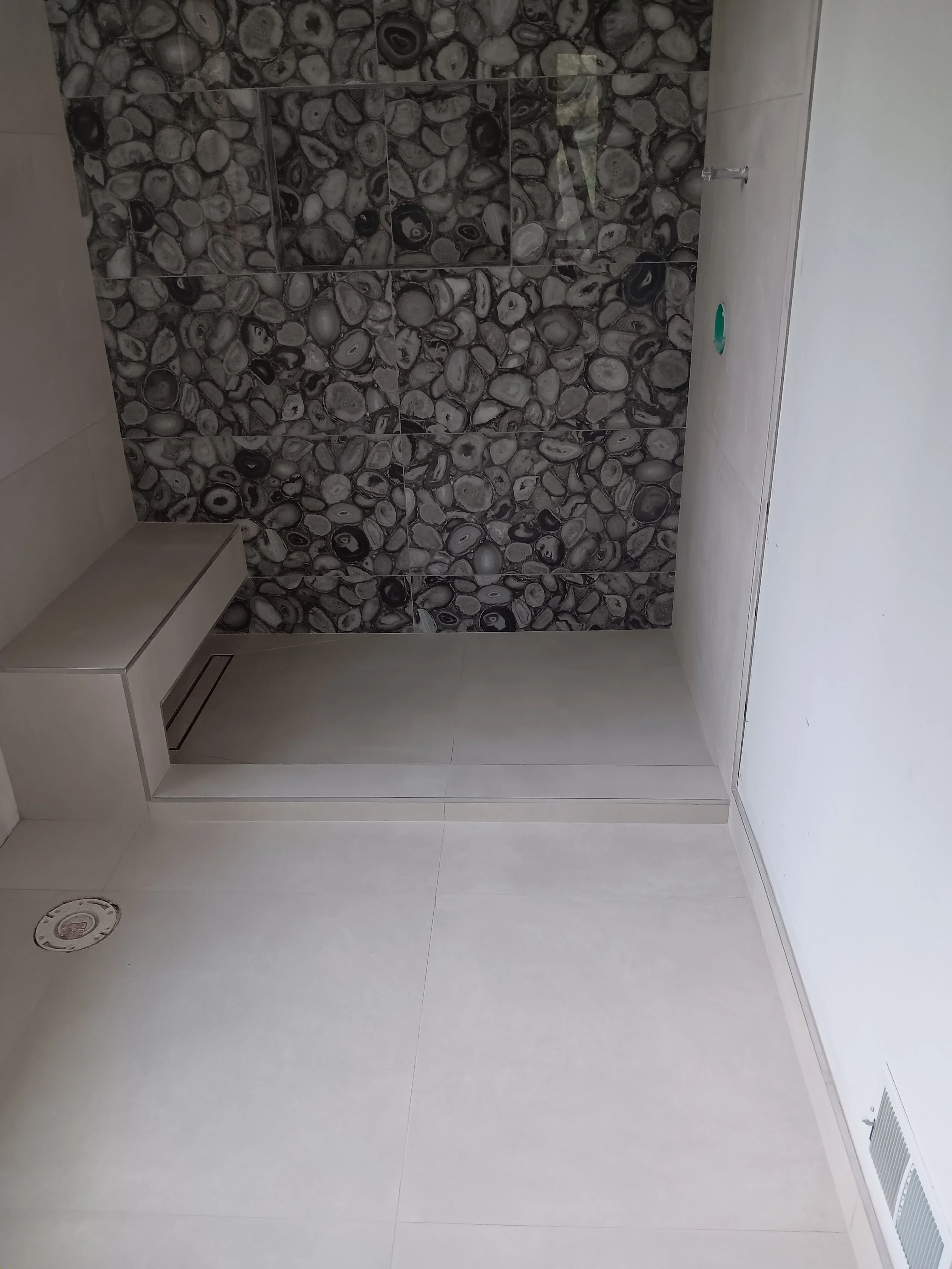 Natural pebble-stone accent wall installed inside the custom shower.