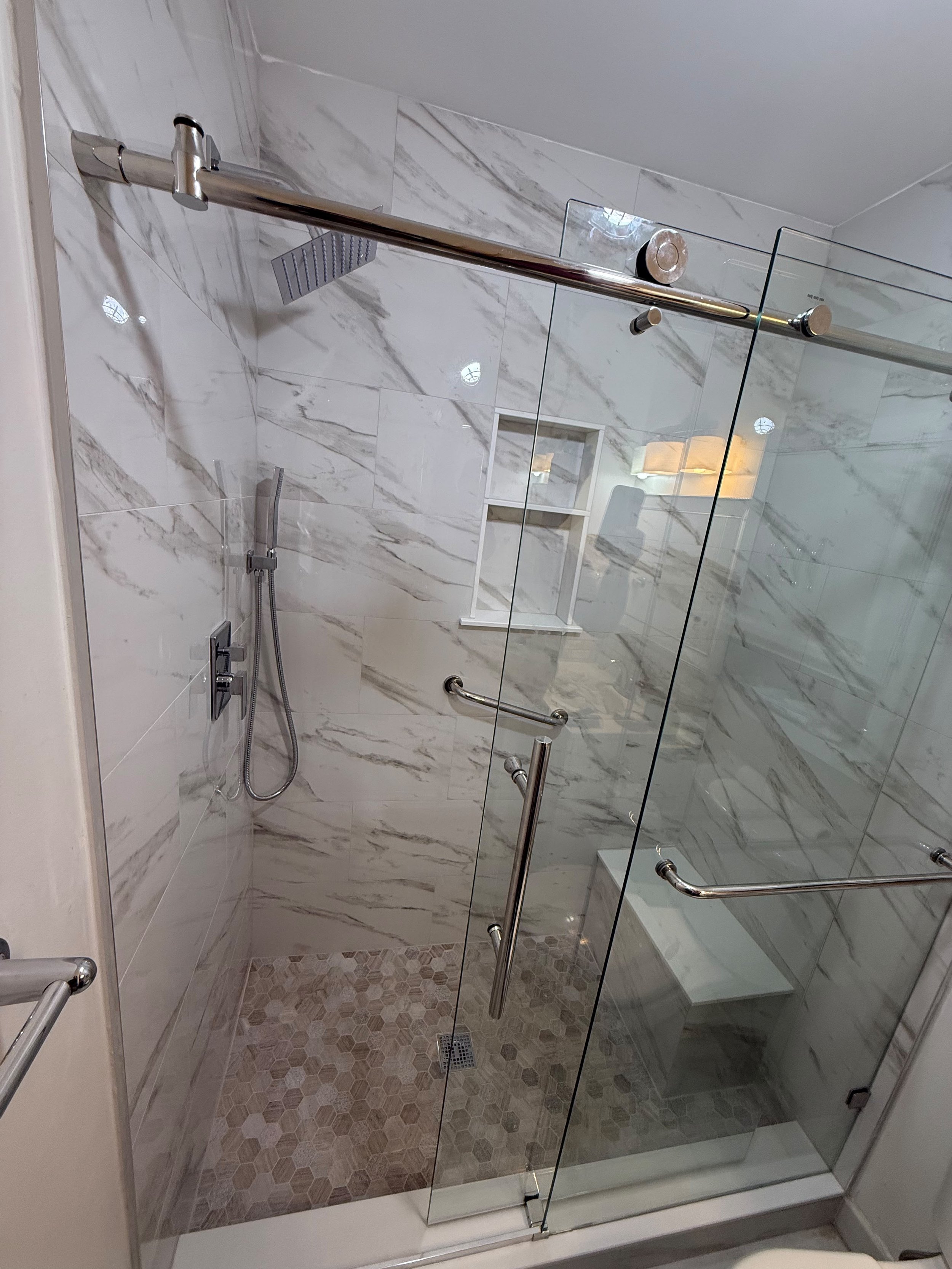 This outdated bathroom was transformed into a modern spa-inspired retreat with large-format marble-look tile, a custom frameless glass shower , built-in storage niches, premium fixtures, and elegant finishes designed for beauty and lasting performanc