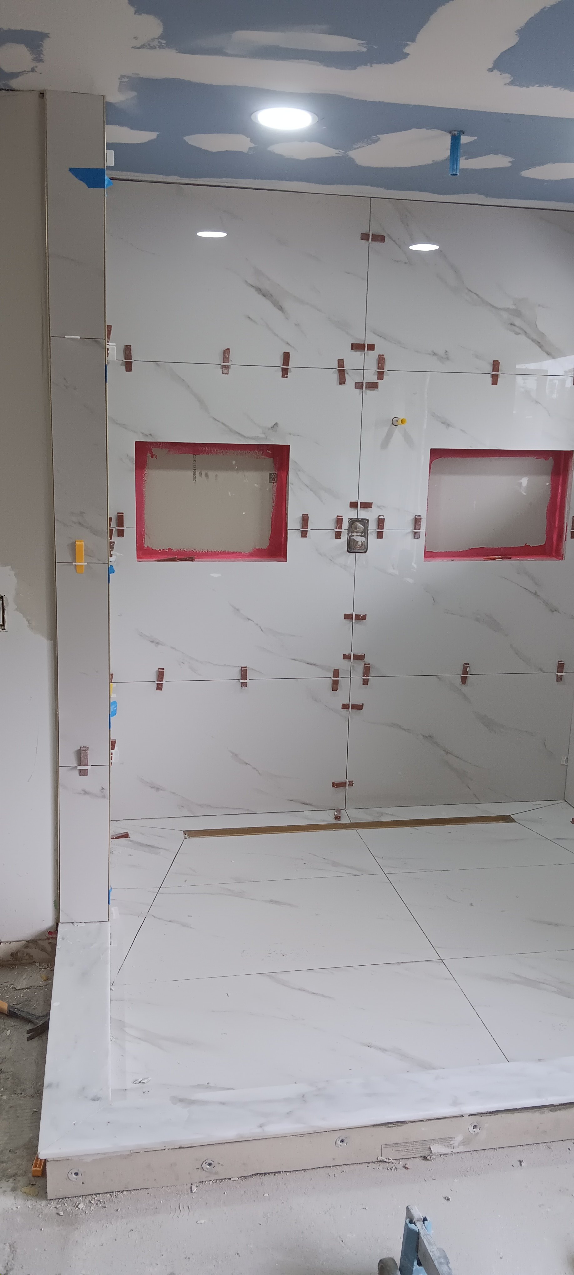 Newly tiled shower wall featuring two built-in storage niches and recessed lighting.