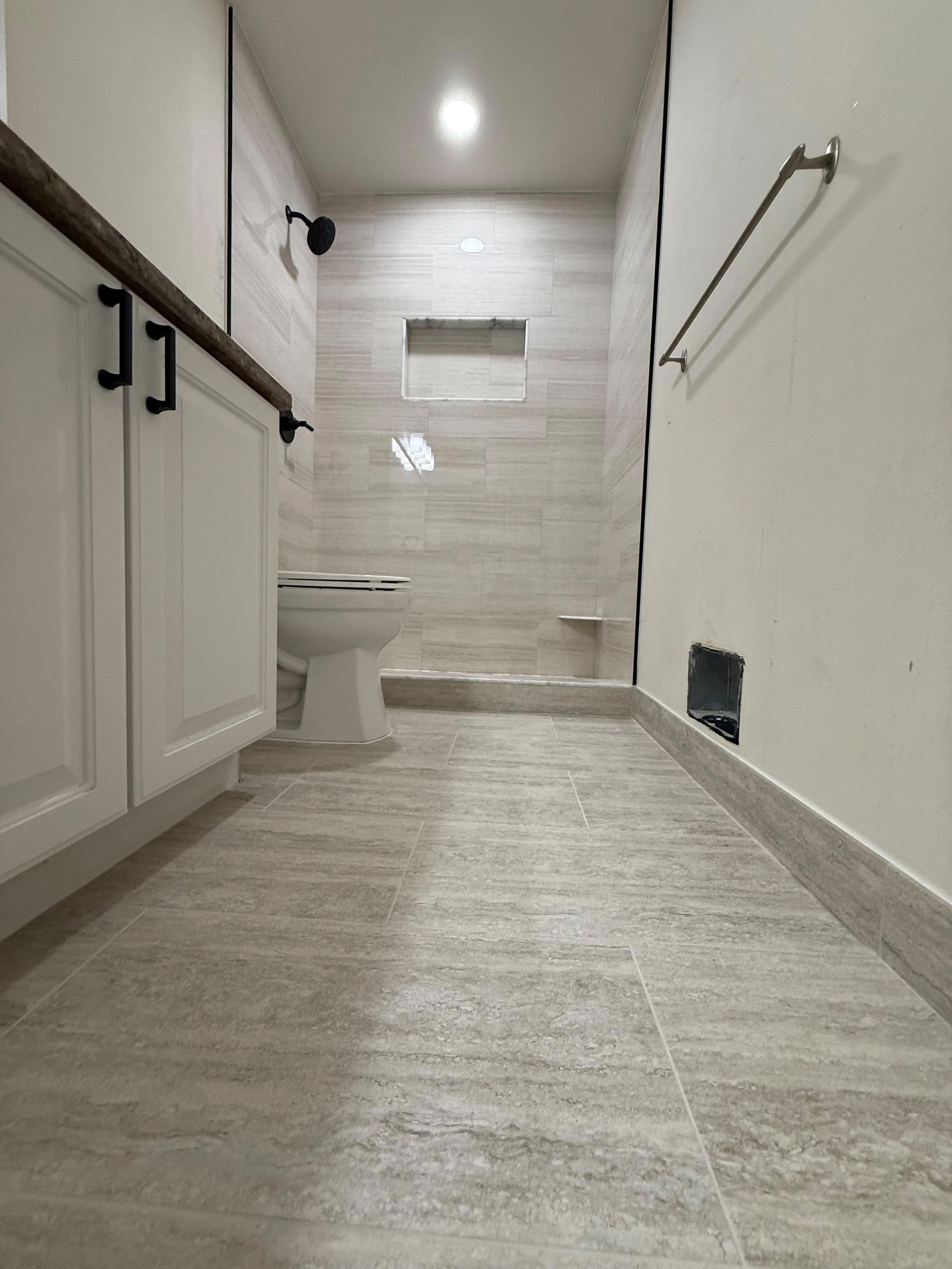 Luxury bathroom remodel with frameless glass shower, custom tile walls, recessed lighting, and modern gray tile flooring by Edilgjoni LLC in Southeast Michigan.