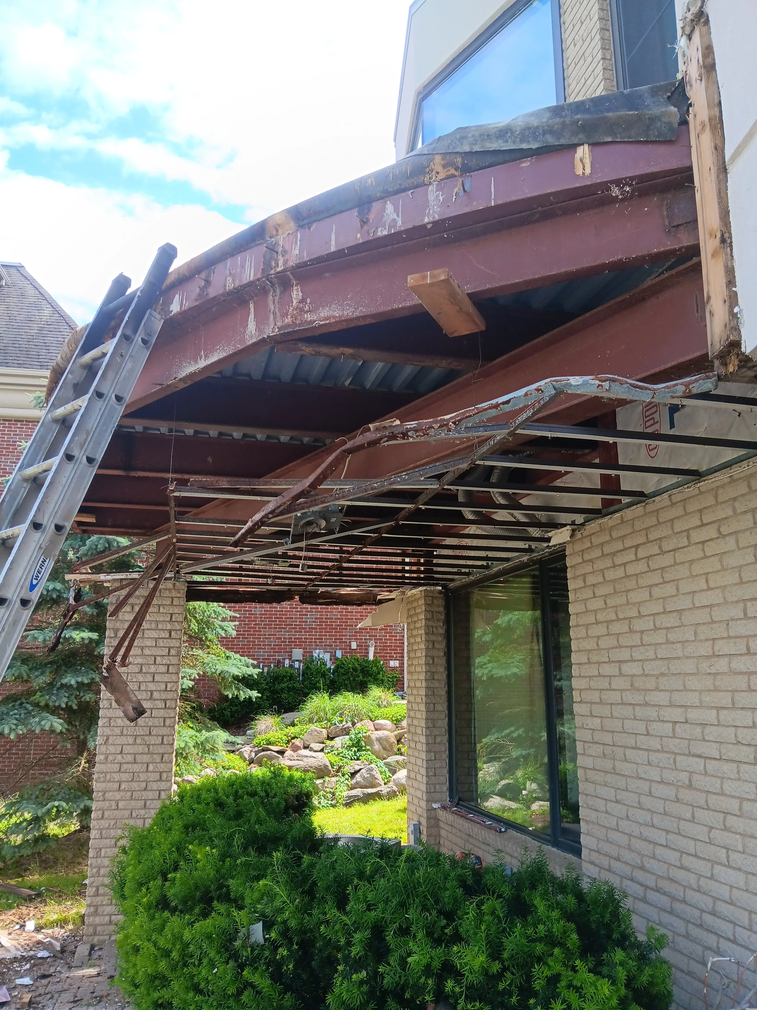 Exposed structural framing beneath a curved balcony during the reconstruction process in rochester Hills, MI.