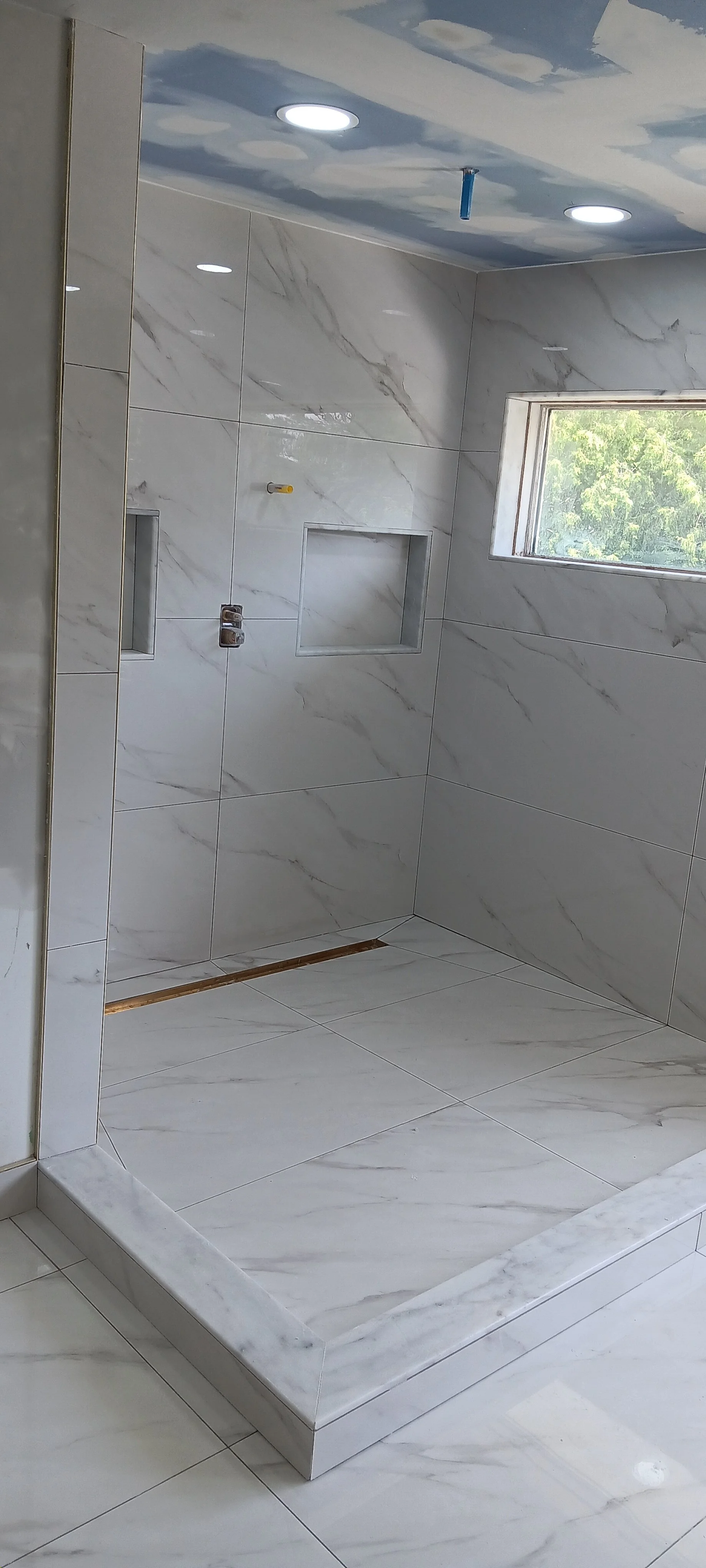 Custom glass shower door with modern hardware and carefully finished tilework.