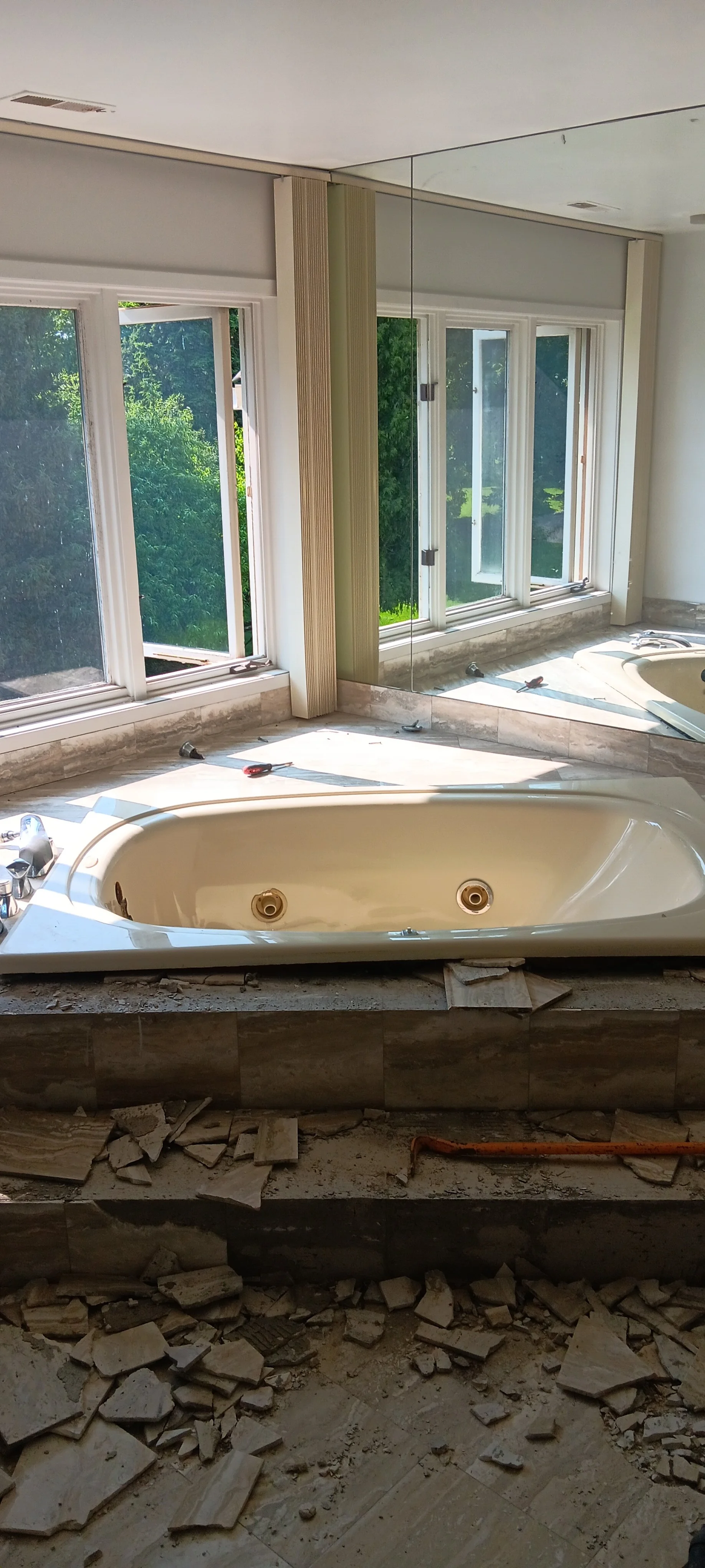 Original bathroom with an outdated bathtub and surrounding fixtures before demolition.
