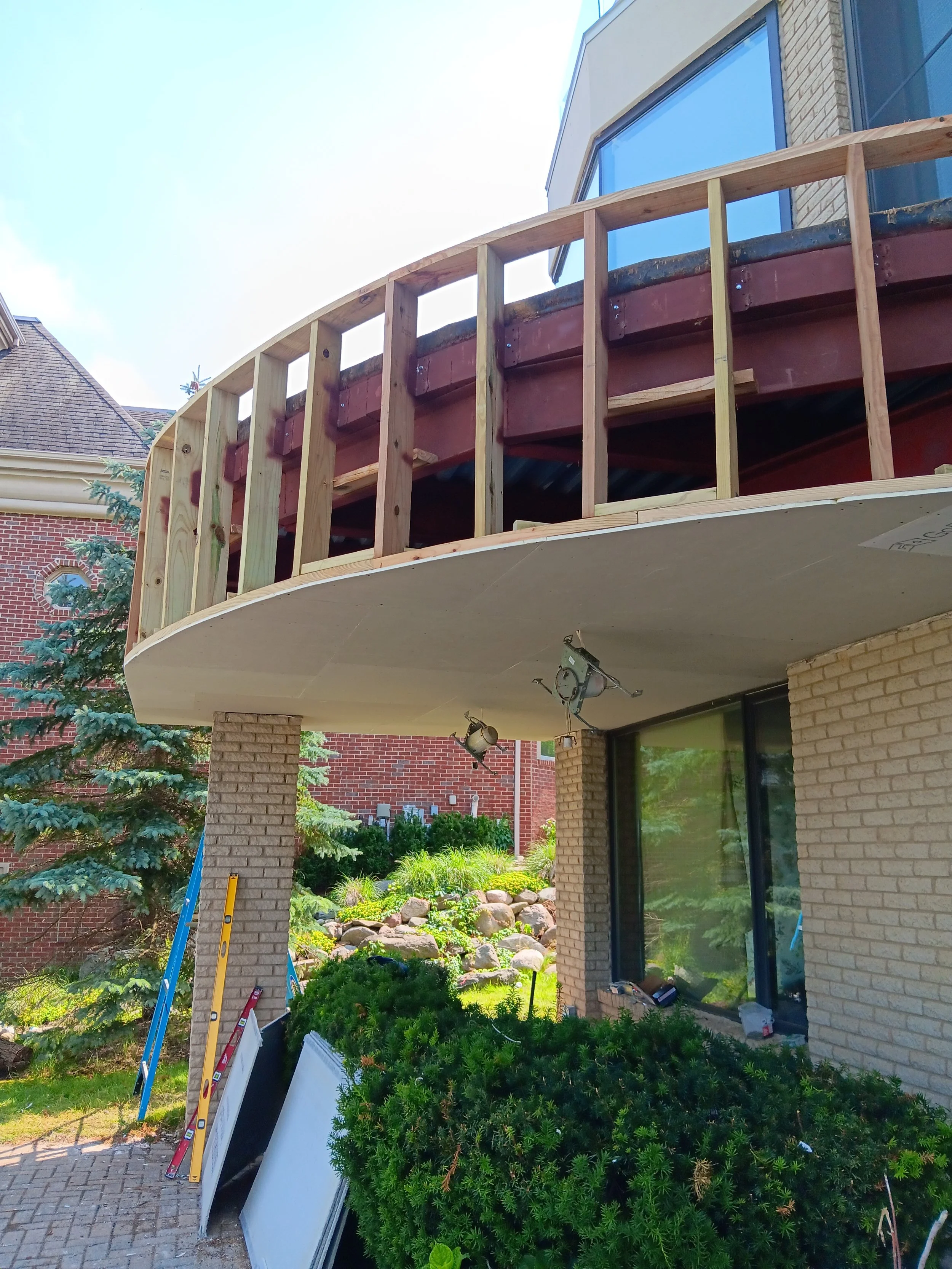 Completed curved balcony restoration featuring a smooth exterior finish and refinished wooden railings.