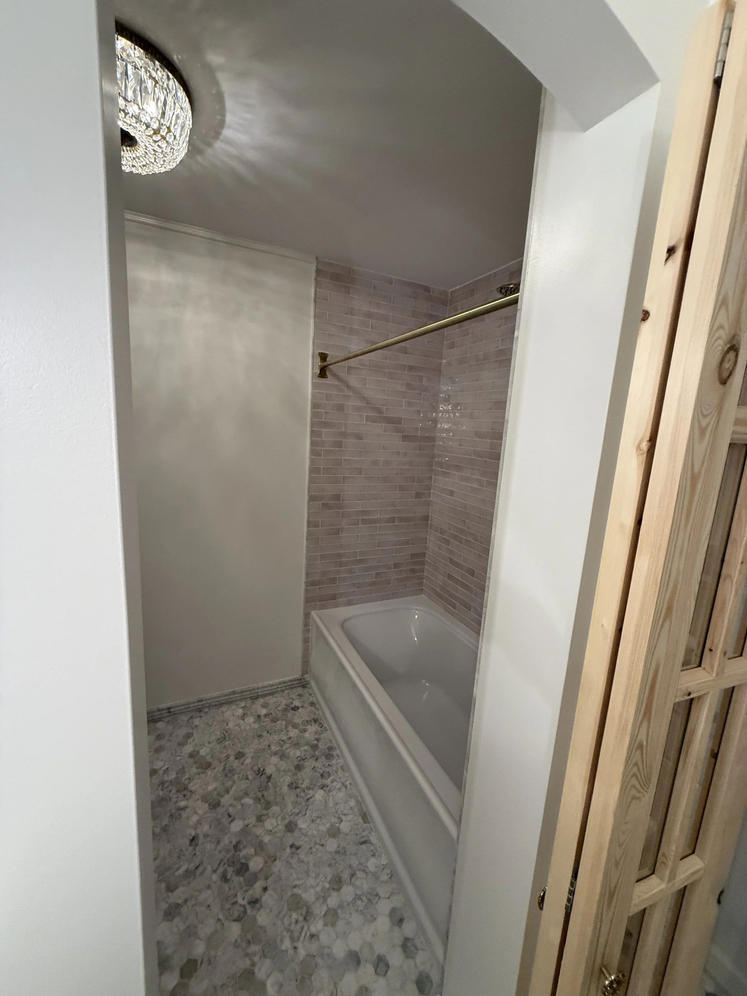 Finished shower and bathtub area with gray tile, mosaic flooring, and modern bathroom fixtures.