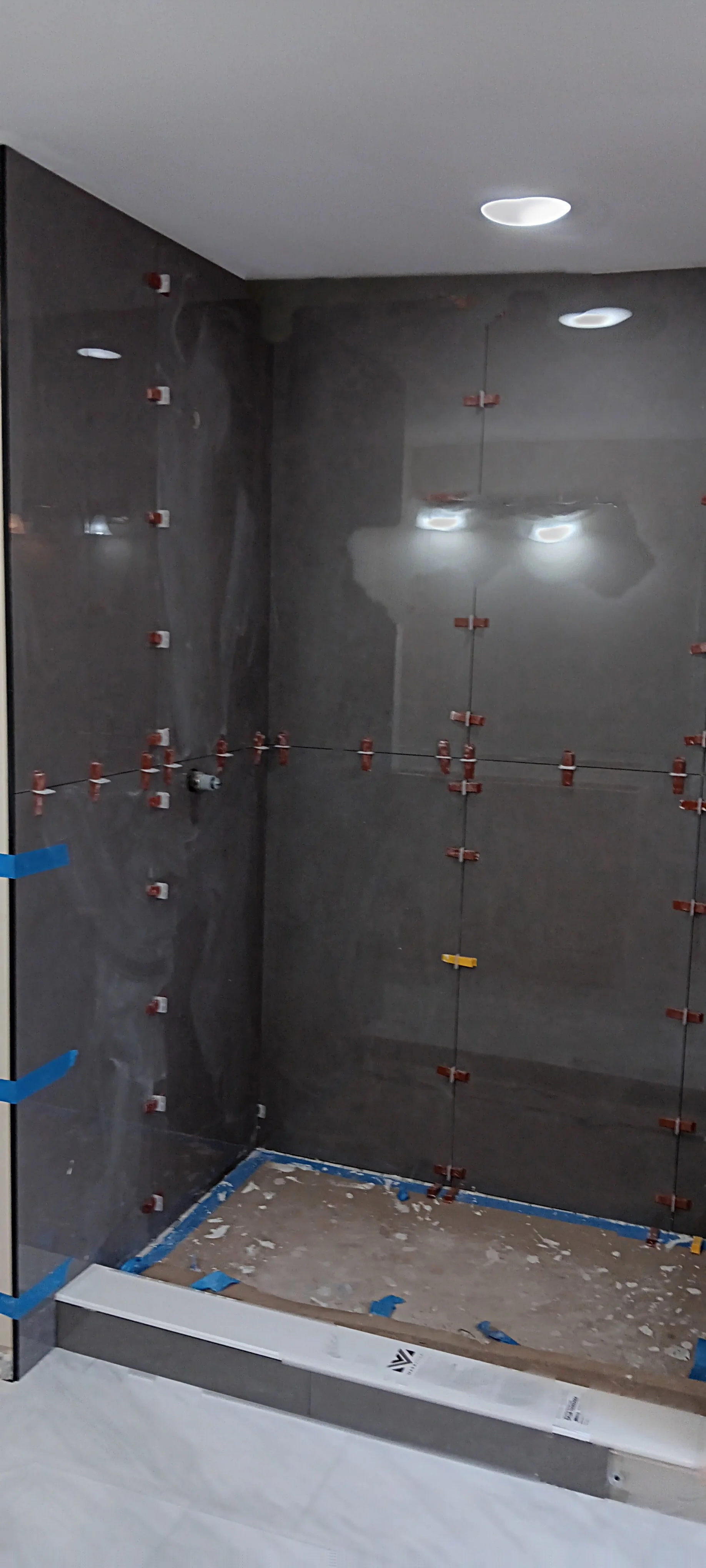 Modern shower walls completed with large-format dark tile and recessed lighting.