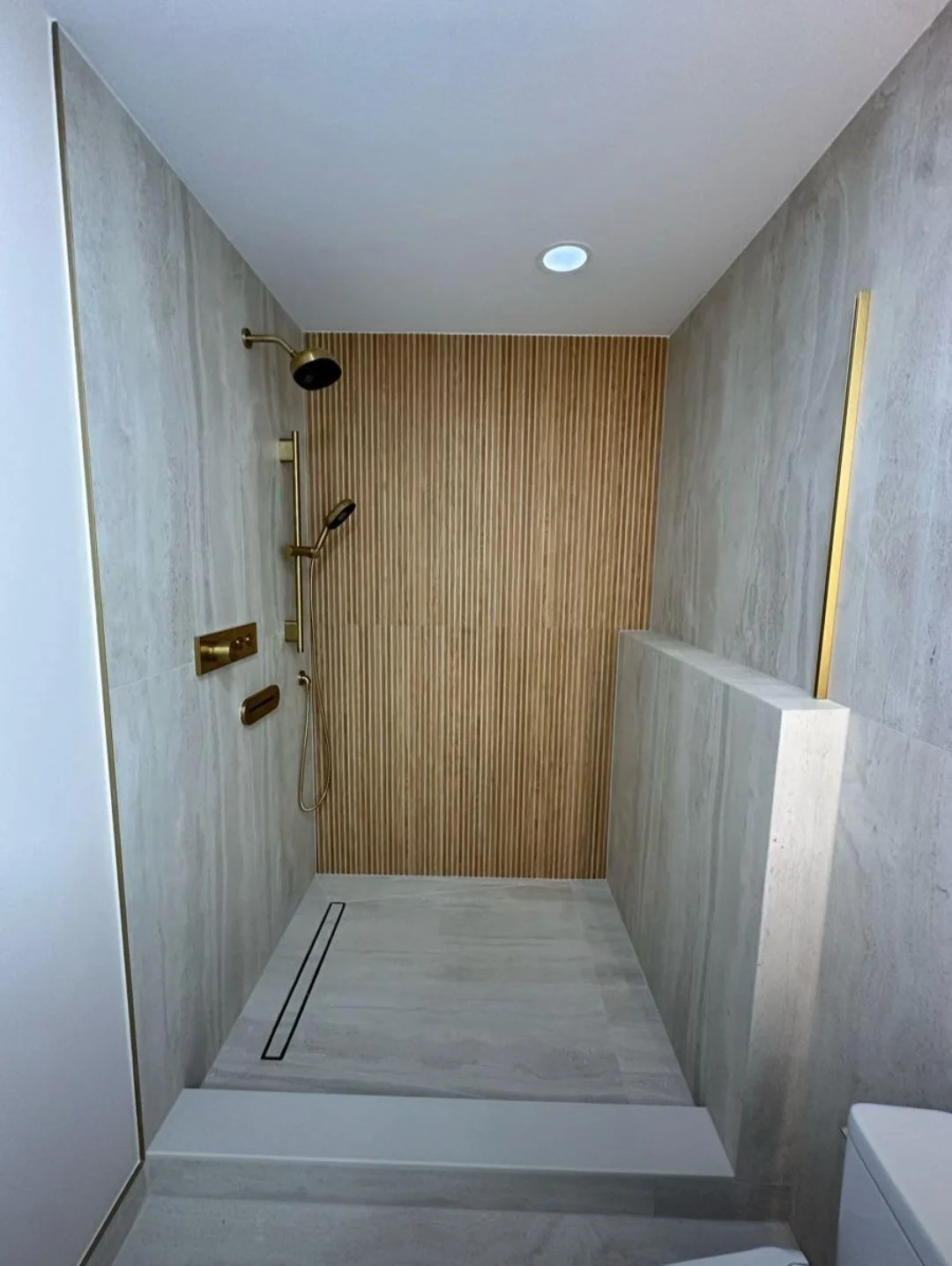 The custom walk-in shower showcases large-format tile, recessed lighting, and a minimalist design that feels open and luxurious.