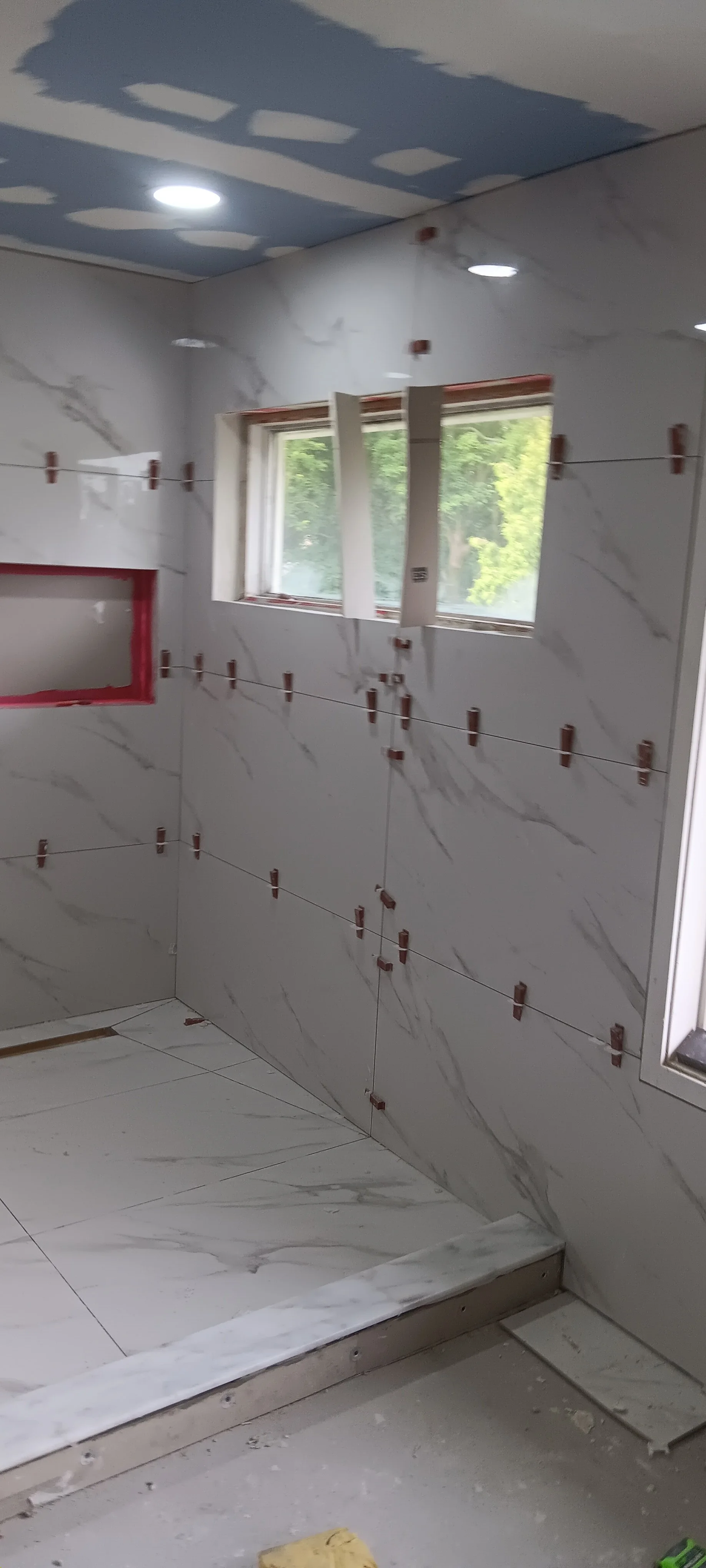 Bathroom walls finished with modern tile around the window and recessed ceiling lights.