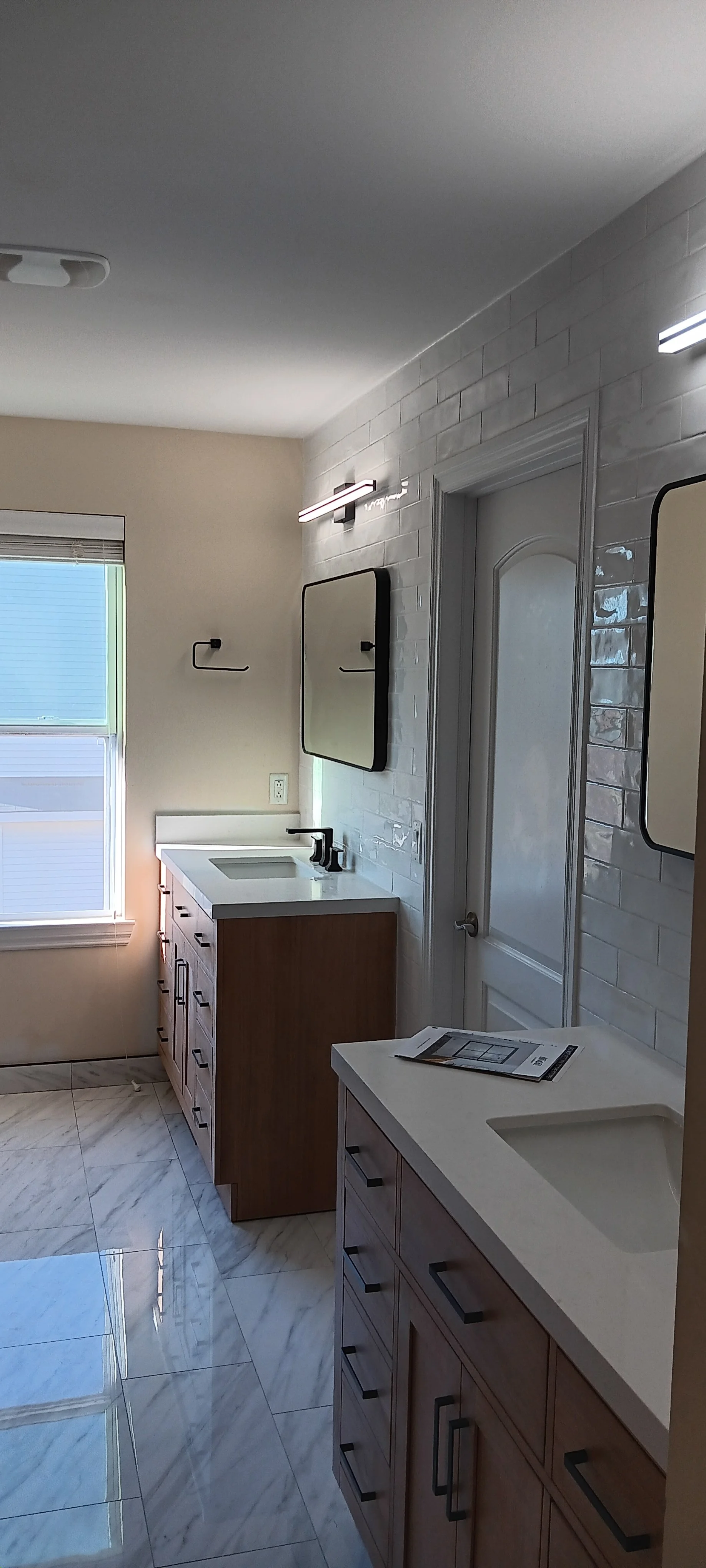 Modern double-vanity bathroom featuring custom cabinetry, illuminated mirrors, stylish lighting, and elegant tile finishes.