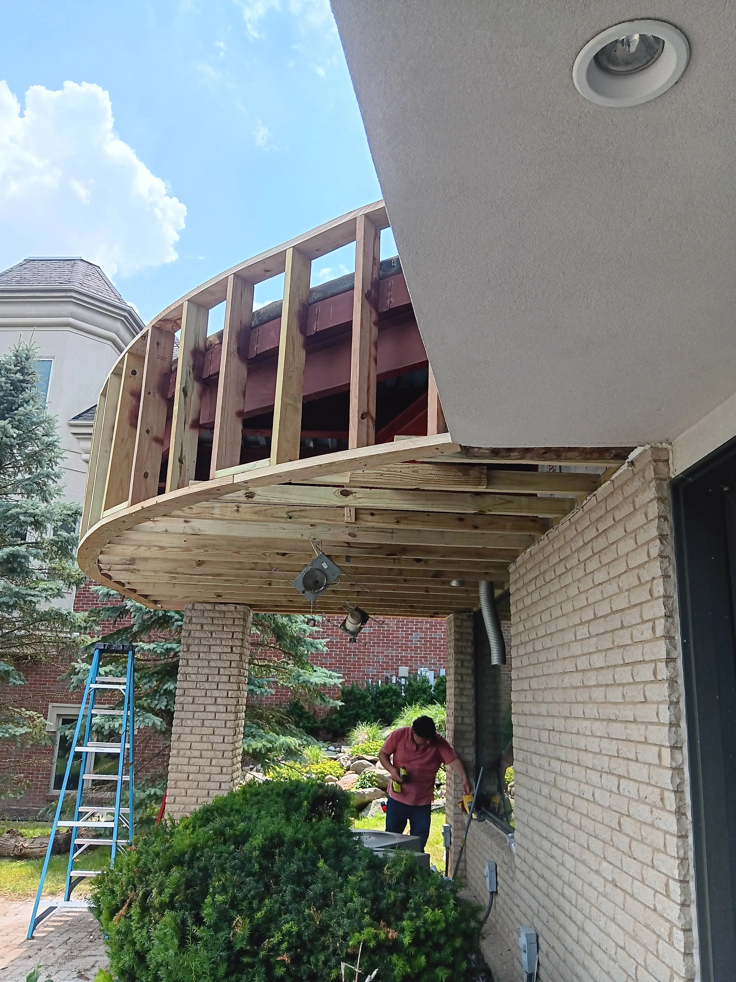 Curved balcony during reconstruction with new framing and preparation for the finished exterior surface.