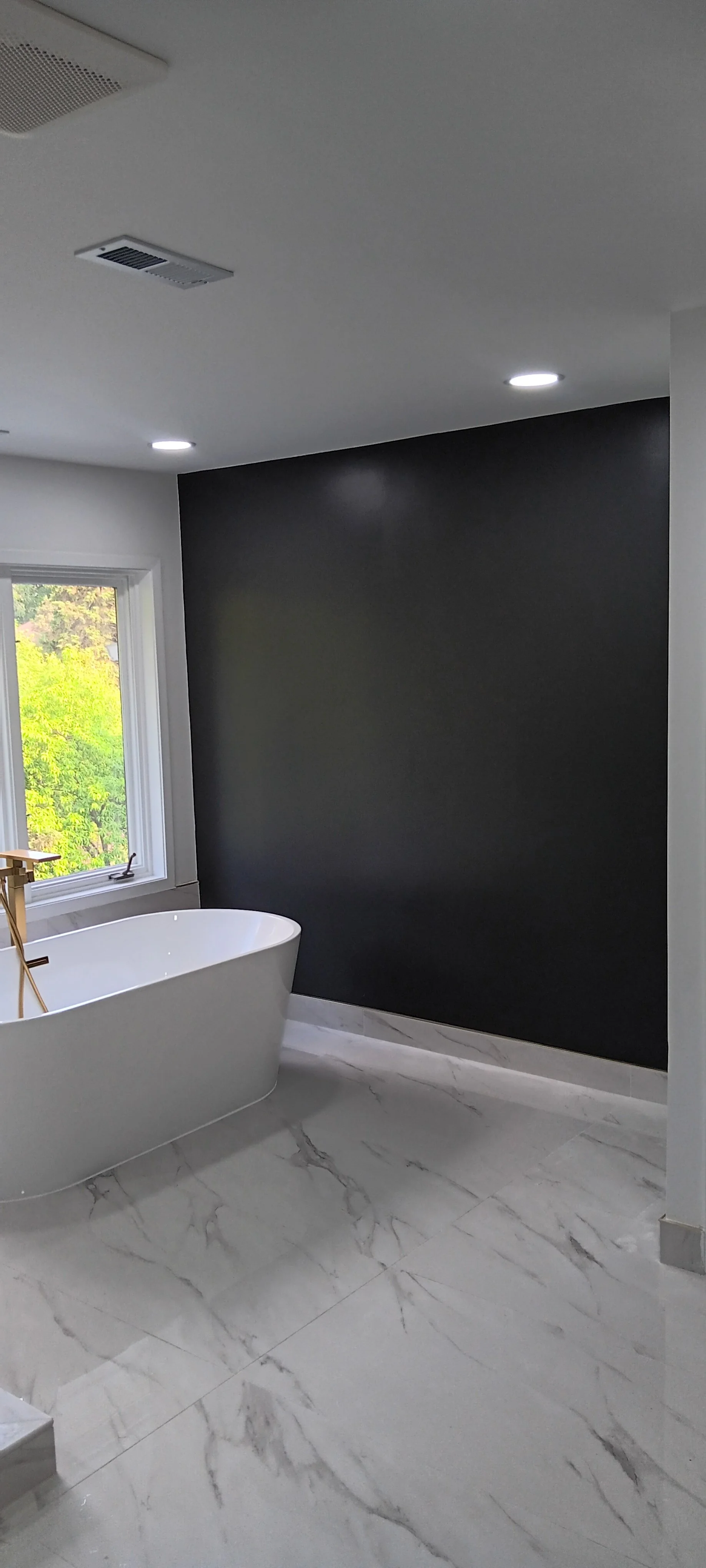 Completed bathroom featuring a freestanding bathtub, tiled floor, recessed lighting, and dark accent walls.