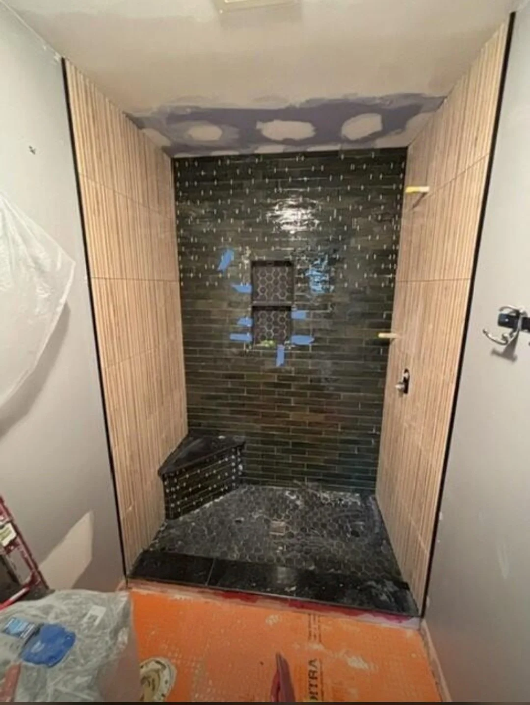 The newly tiled walk-in shower features elegant dark ceramic tile and expert craftsmanship , creating a bold, modern appearance.