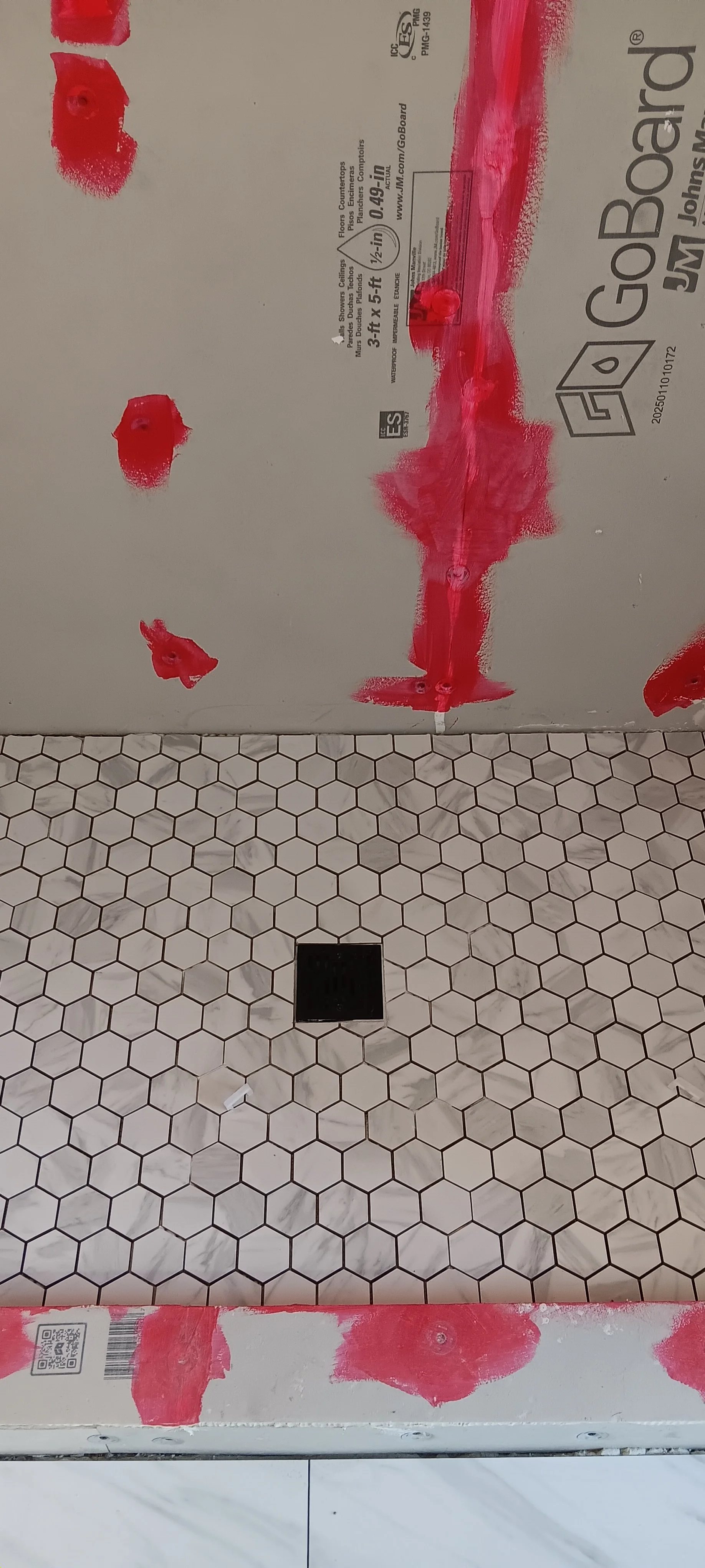 Close-up of the mosaic shower floor with a square center drain.